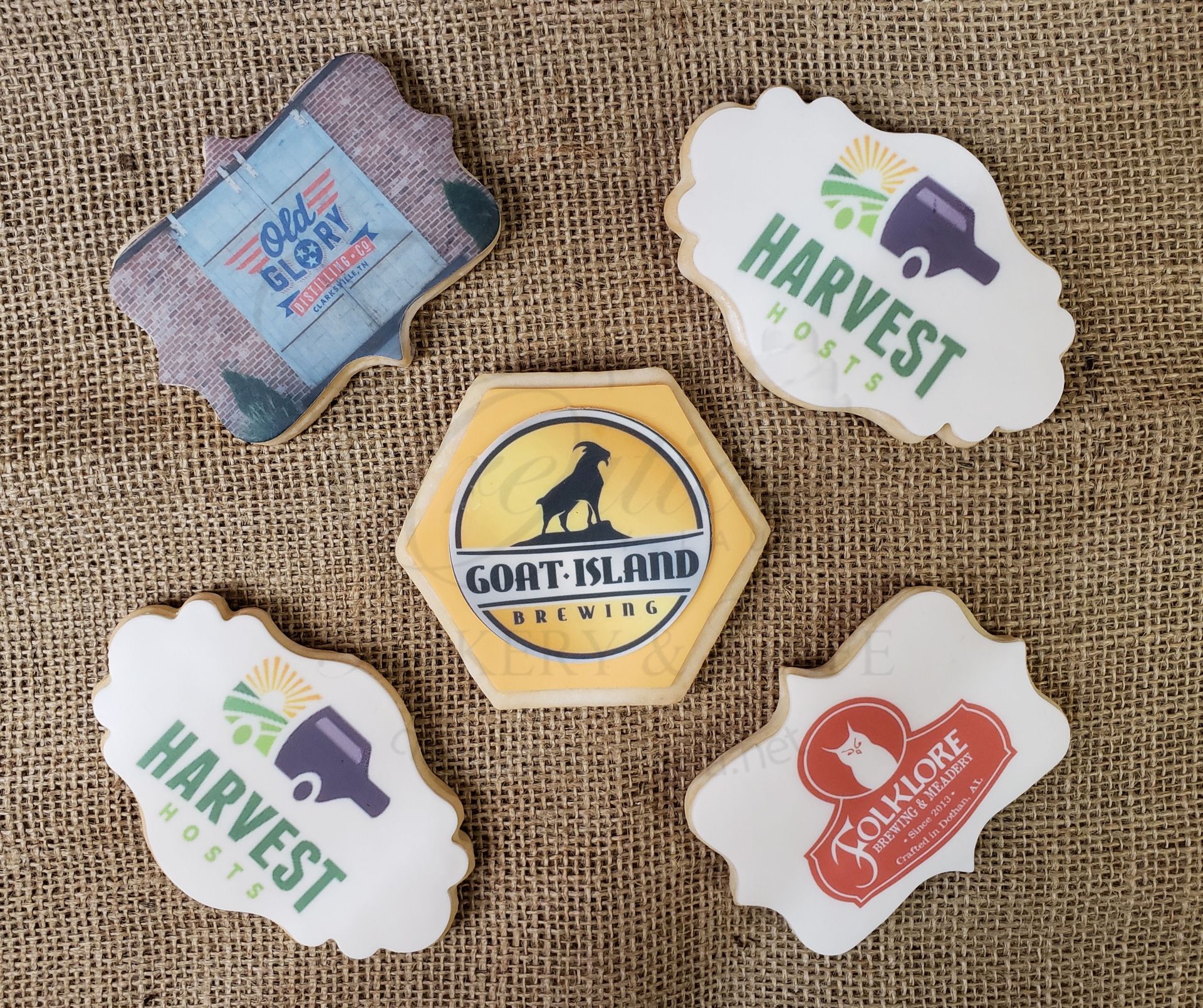 Assorted branded stickers on burlap, including green HARVEST and yellow GOAT-ISLAND labels.