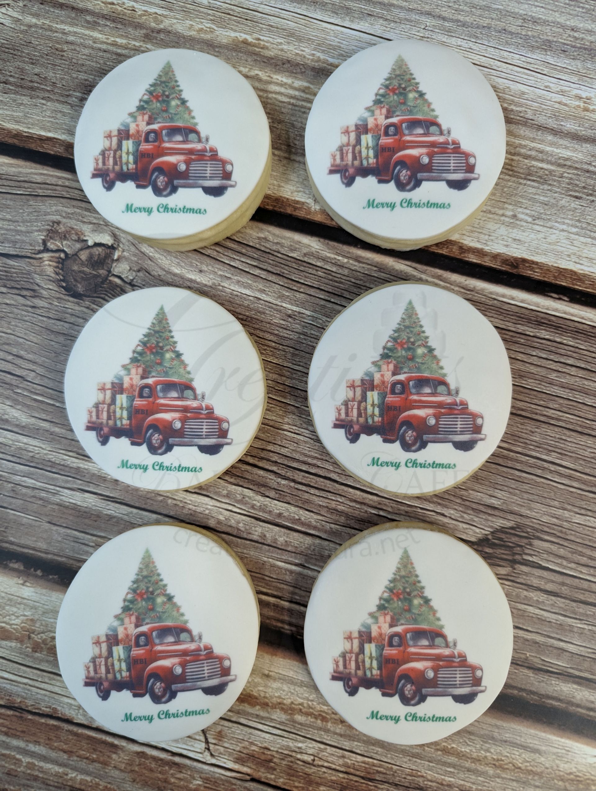 Six round Christmas ornaments with red trucks and trees on a gray fabric background.
