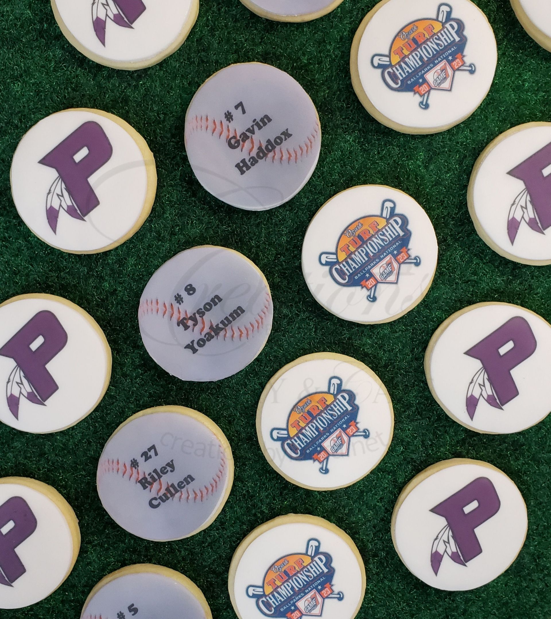 Assorted round pins with purple, silver, and orange logos scattered on green grass.