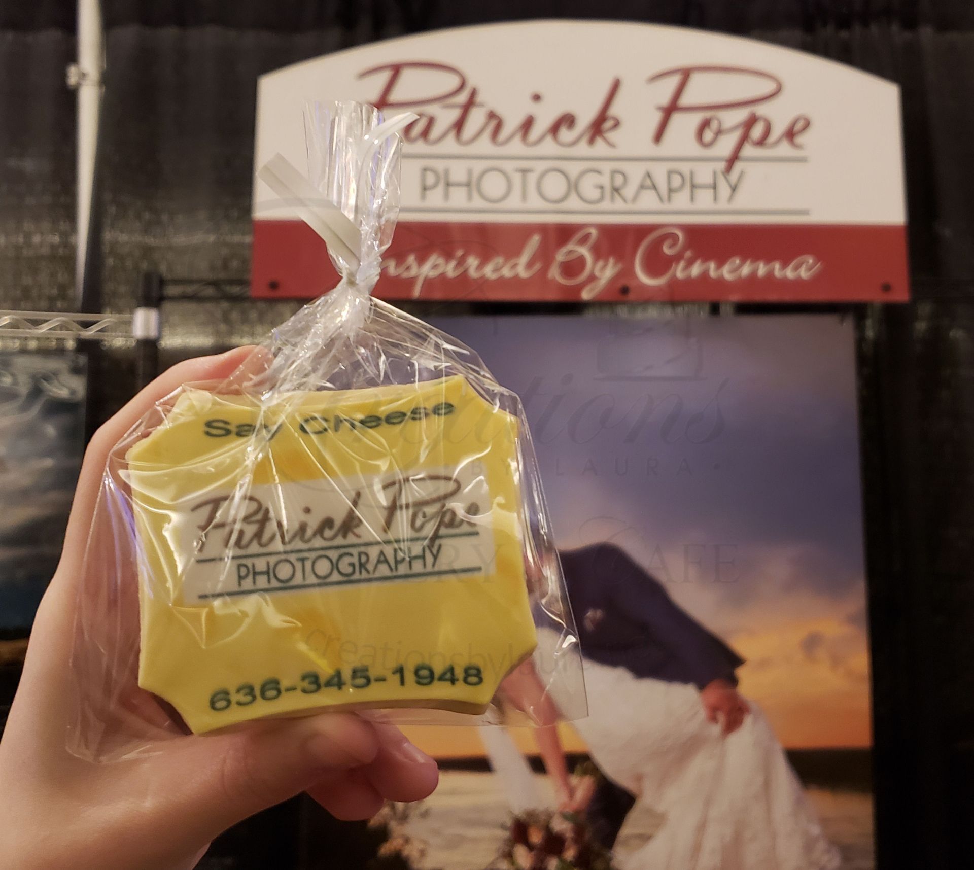 Hand holding a yellow Patrick Foye Photography card in front of a matching display sign.