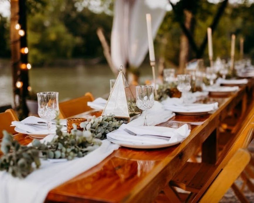 A long wooden table is set for a wedding reception