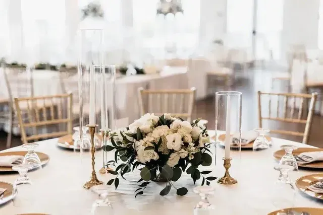 A table with a vase of flowers and candles on it.