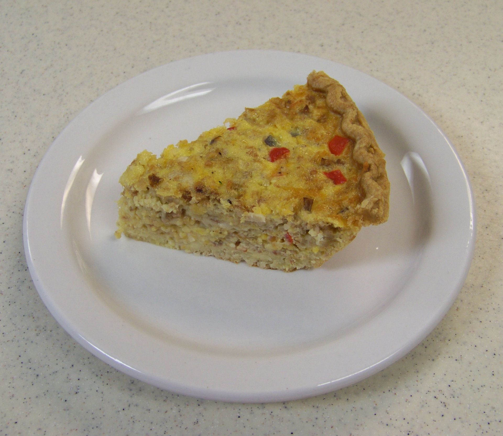 a white plate with a slice of quiche on it