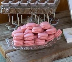 A glass plate filled with pink macarons and chocolate cake pops on a wooden table.