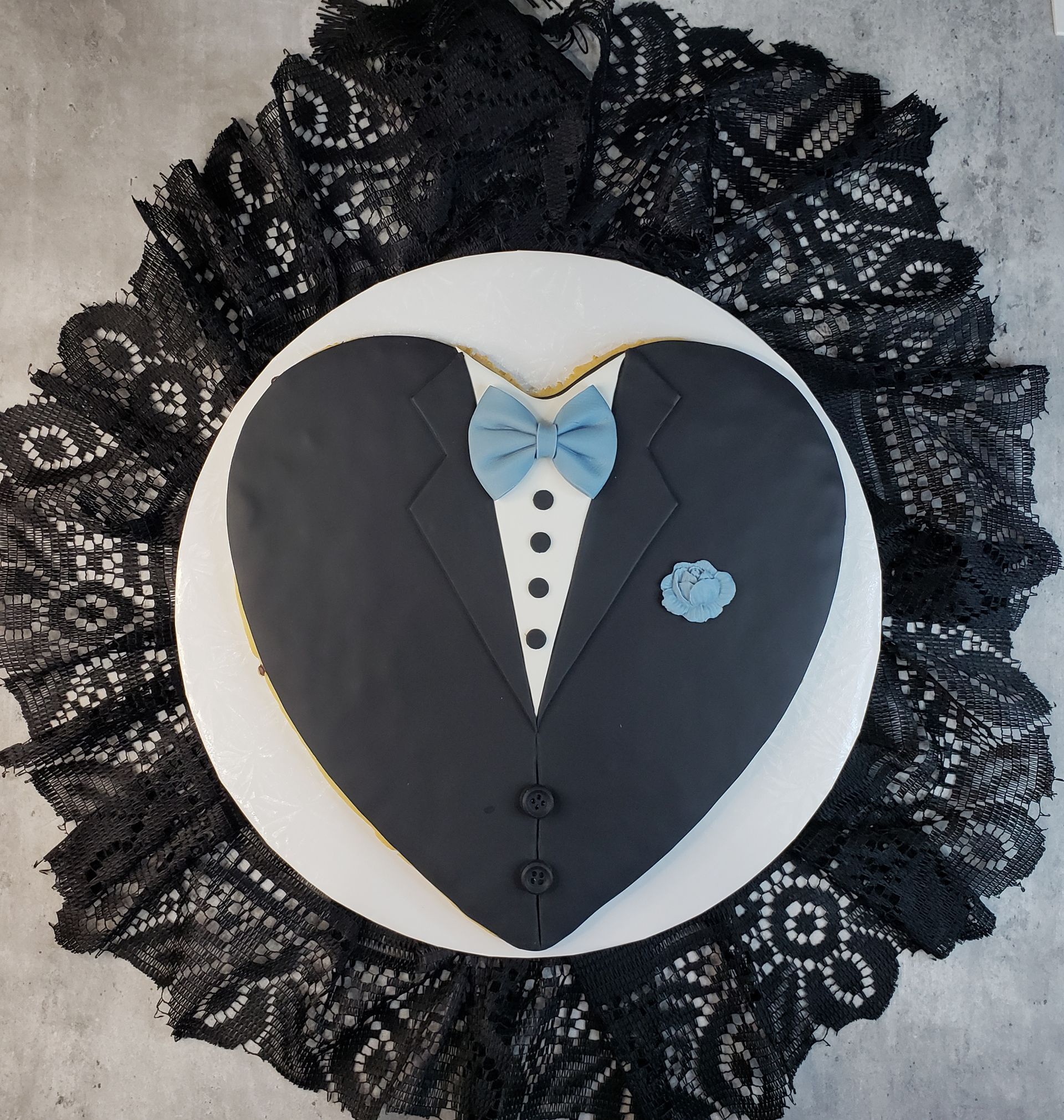 A heart shaped cake with a tuxedo and bow tie