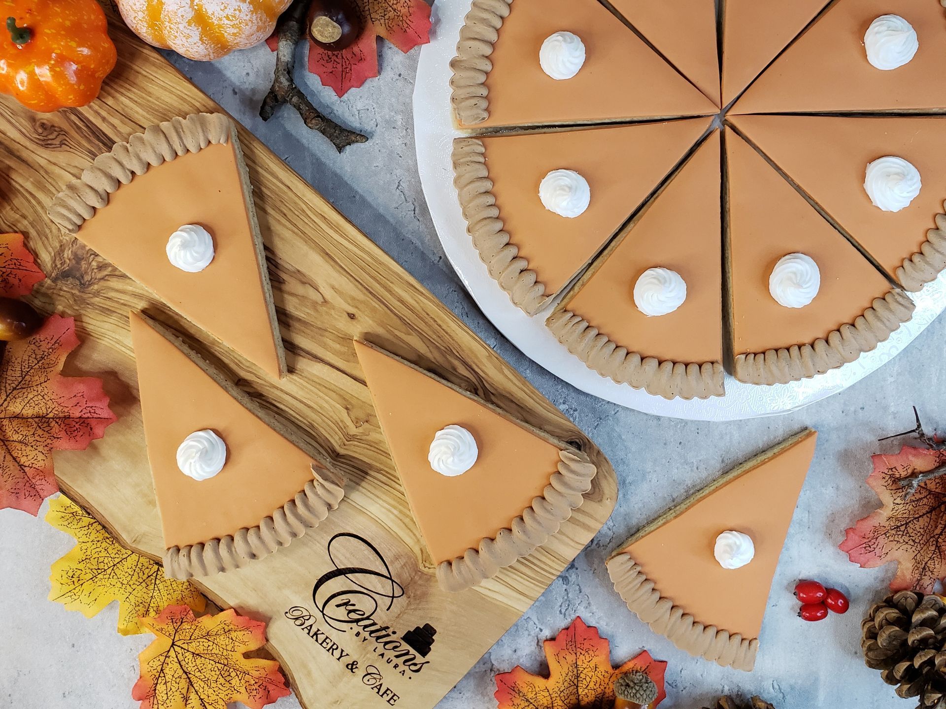 Slices of pumpkin pie are sitting on a wooden cutting board.