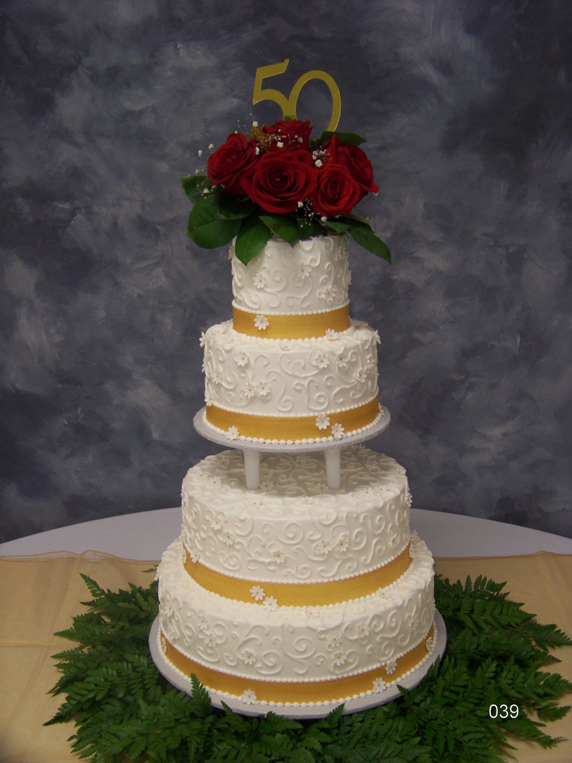 Five-tier white and gold cake with red roses and a gold 