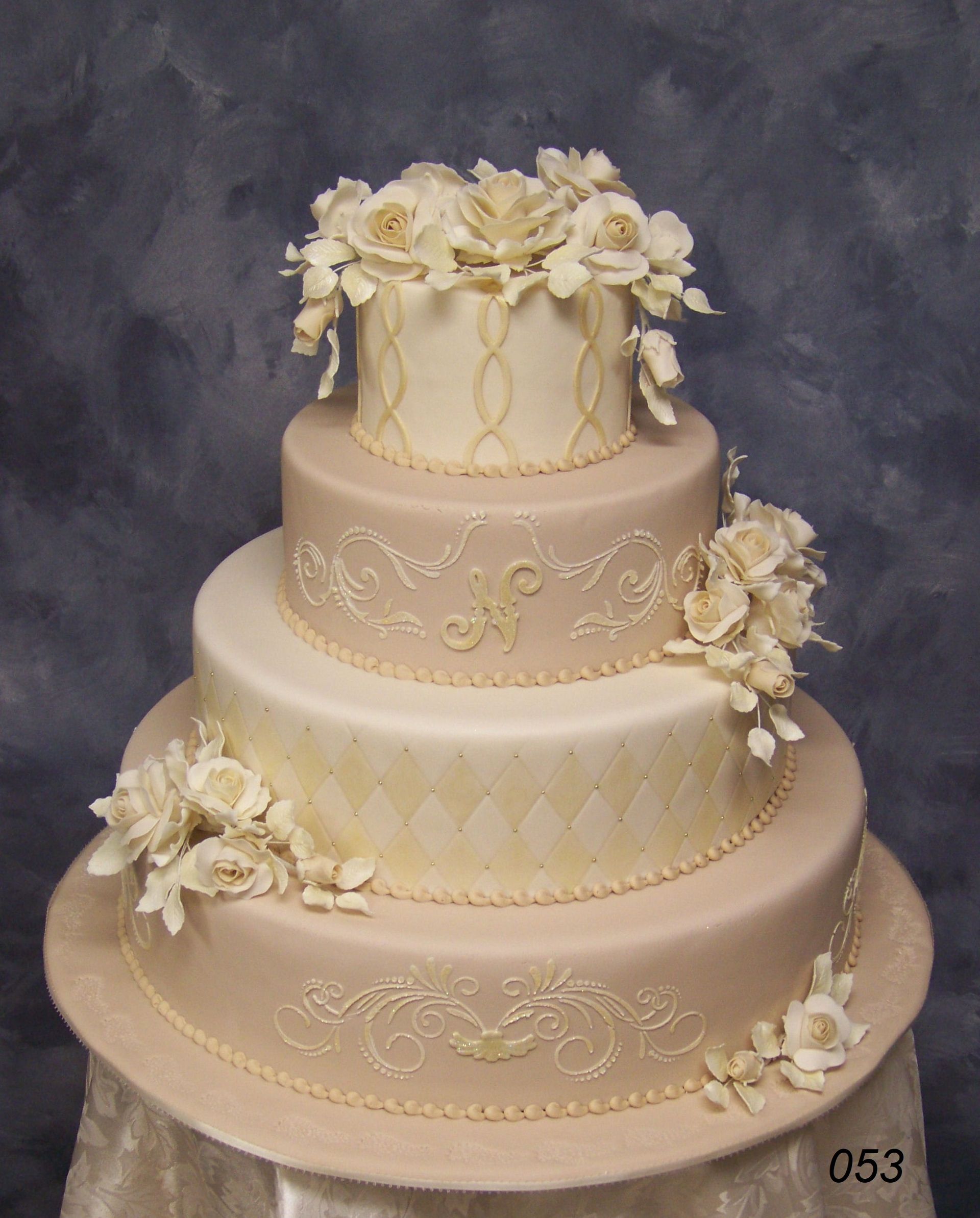 Three-tier ivory wedding cake with cream floral decorations and gold accents