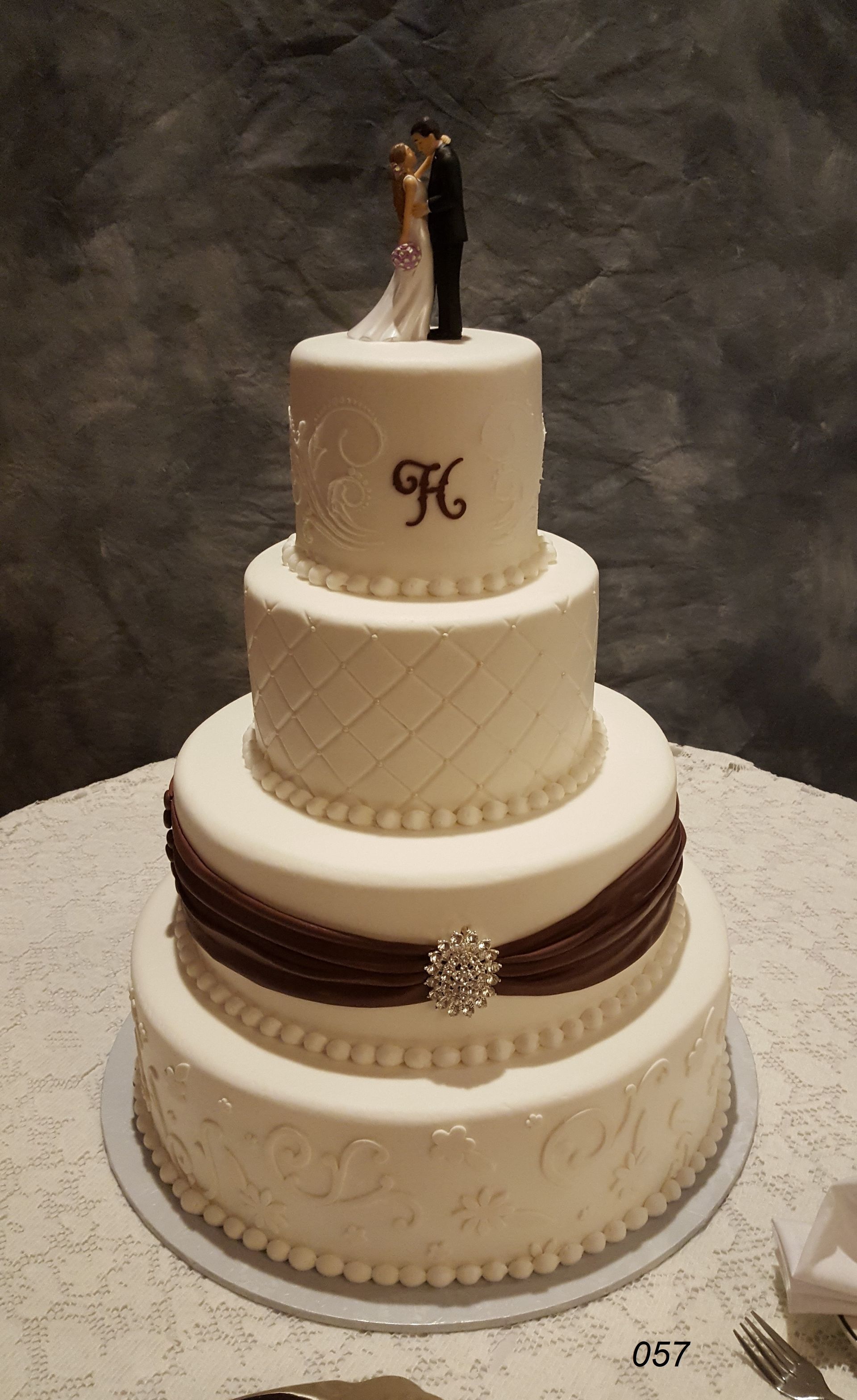 Tiered ivory wedding cake with gold accents and a bride-and-groom topper