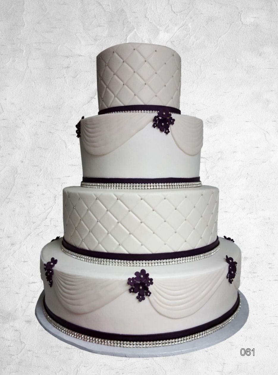 Four-tier white wedding cake with silver trim and purple floral accents