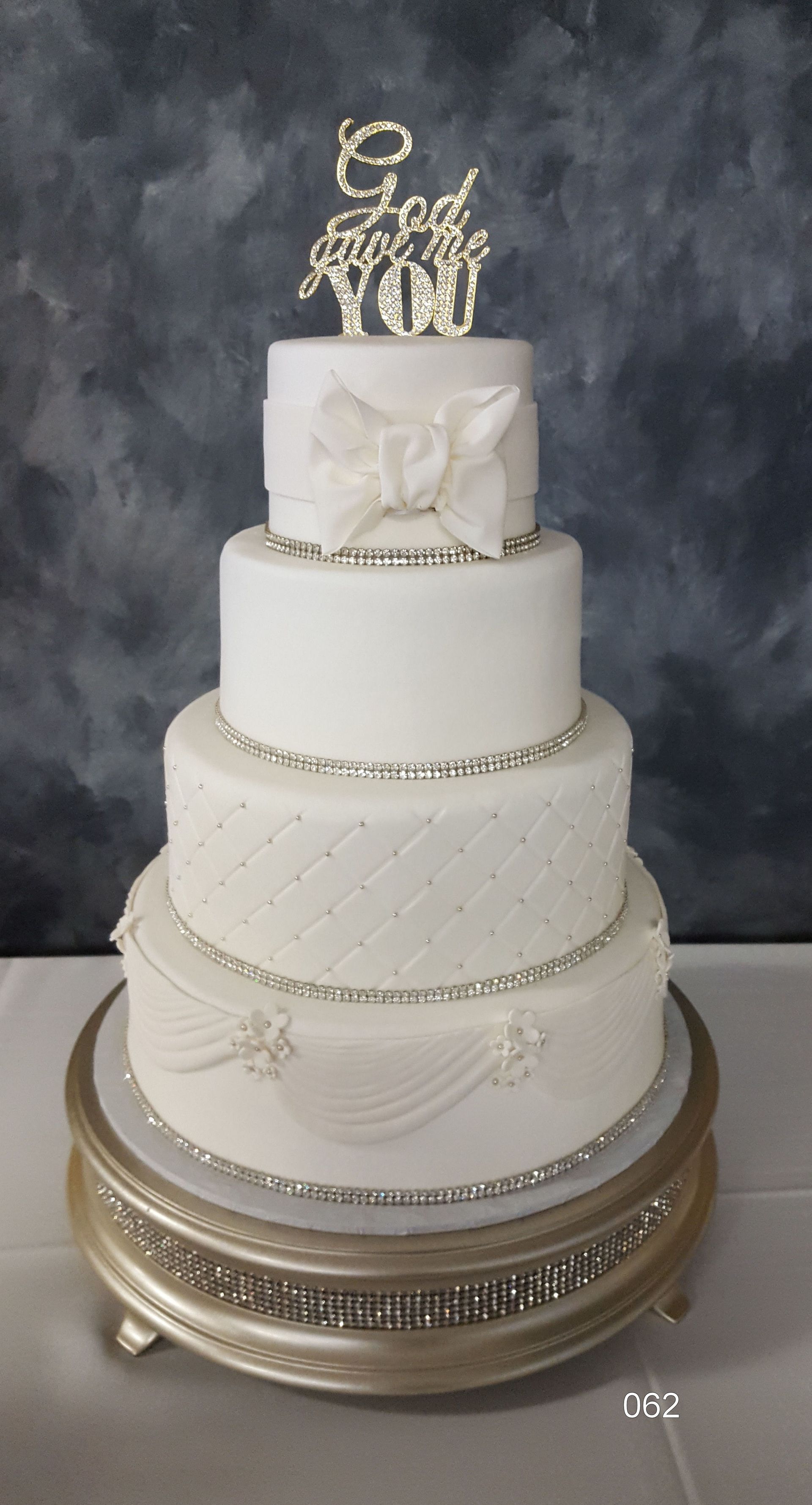 Elegant white multi-tier wedding cake with gold accents on a decorated stand