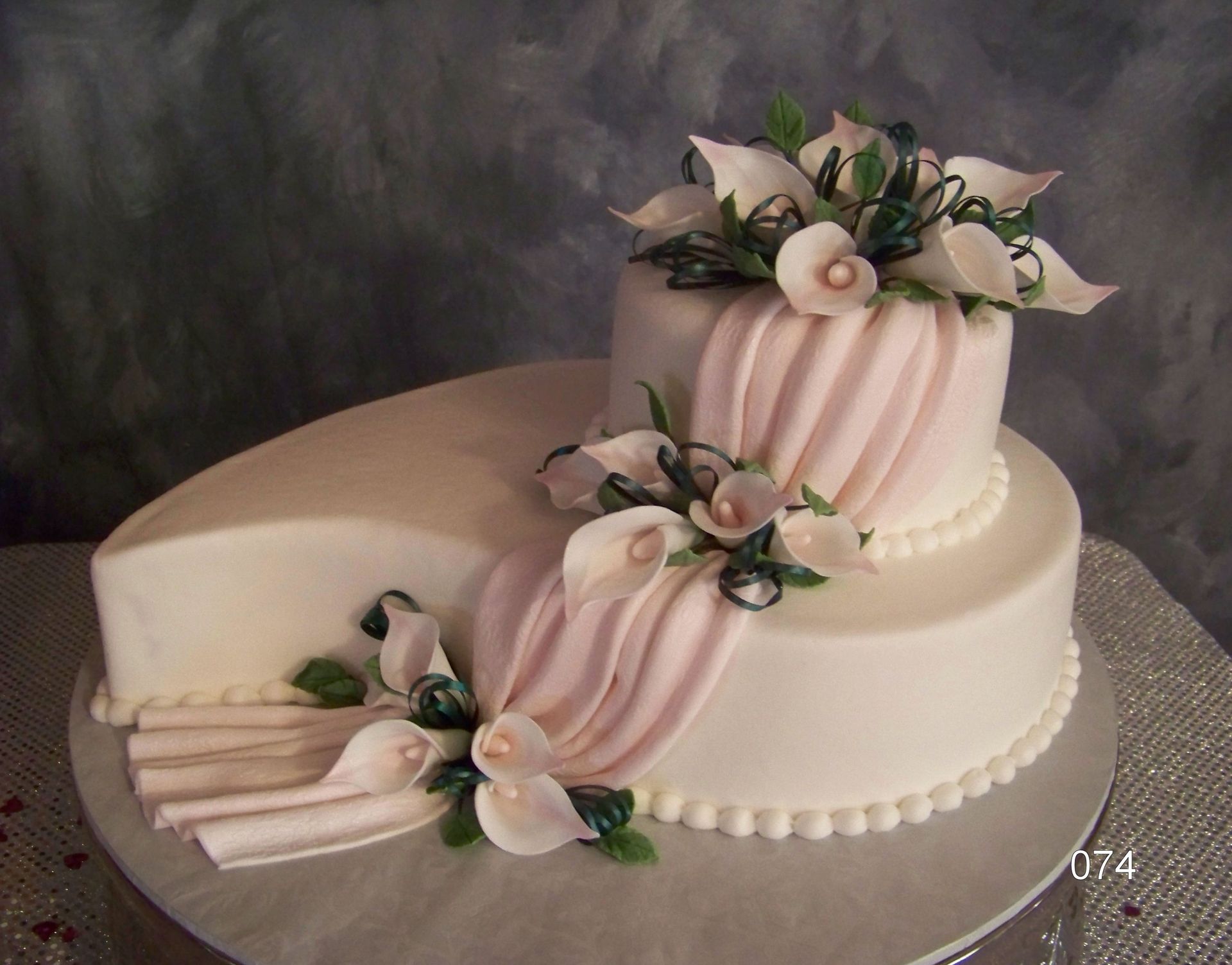 Pink and white tiered cake with floral decorations on a silver platter