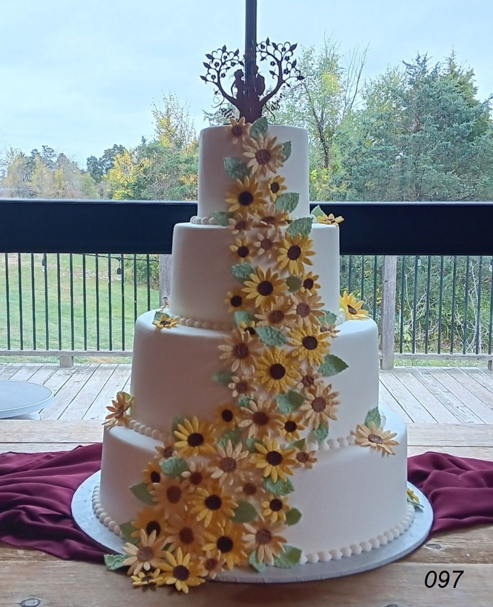 White tiered wedding cake with yellow sunflower decorations on a table by a window