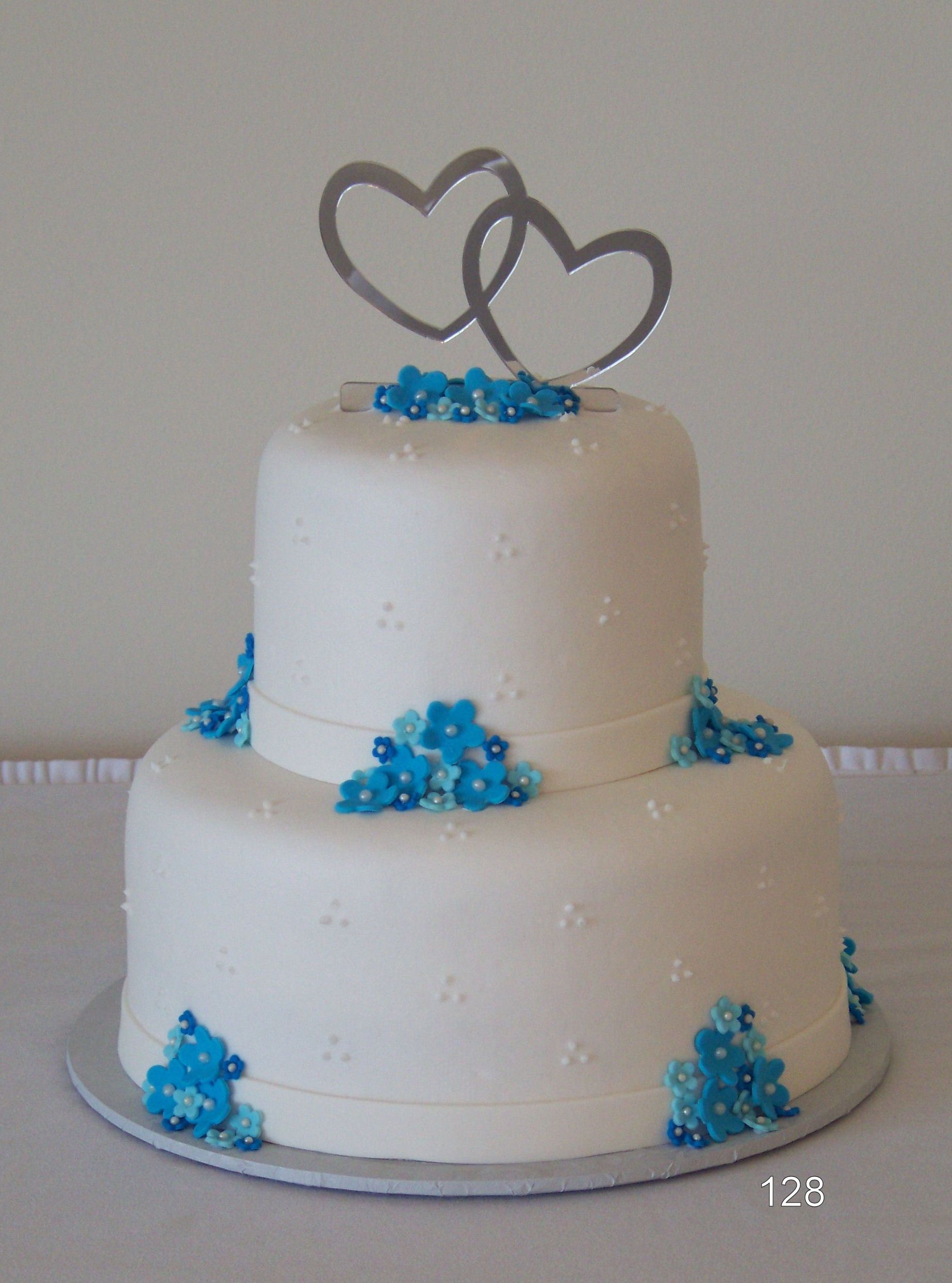 White two-tier cake with blue flowers and silver heart toppers