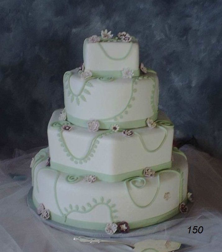 Four-tier white wedding cake with pale green vine and floral decorations