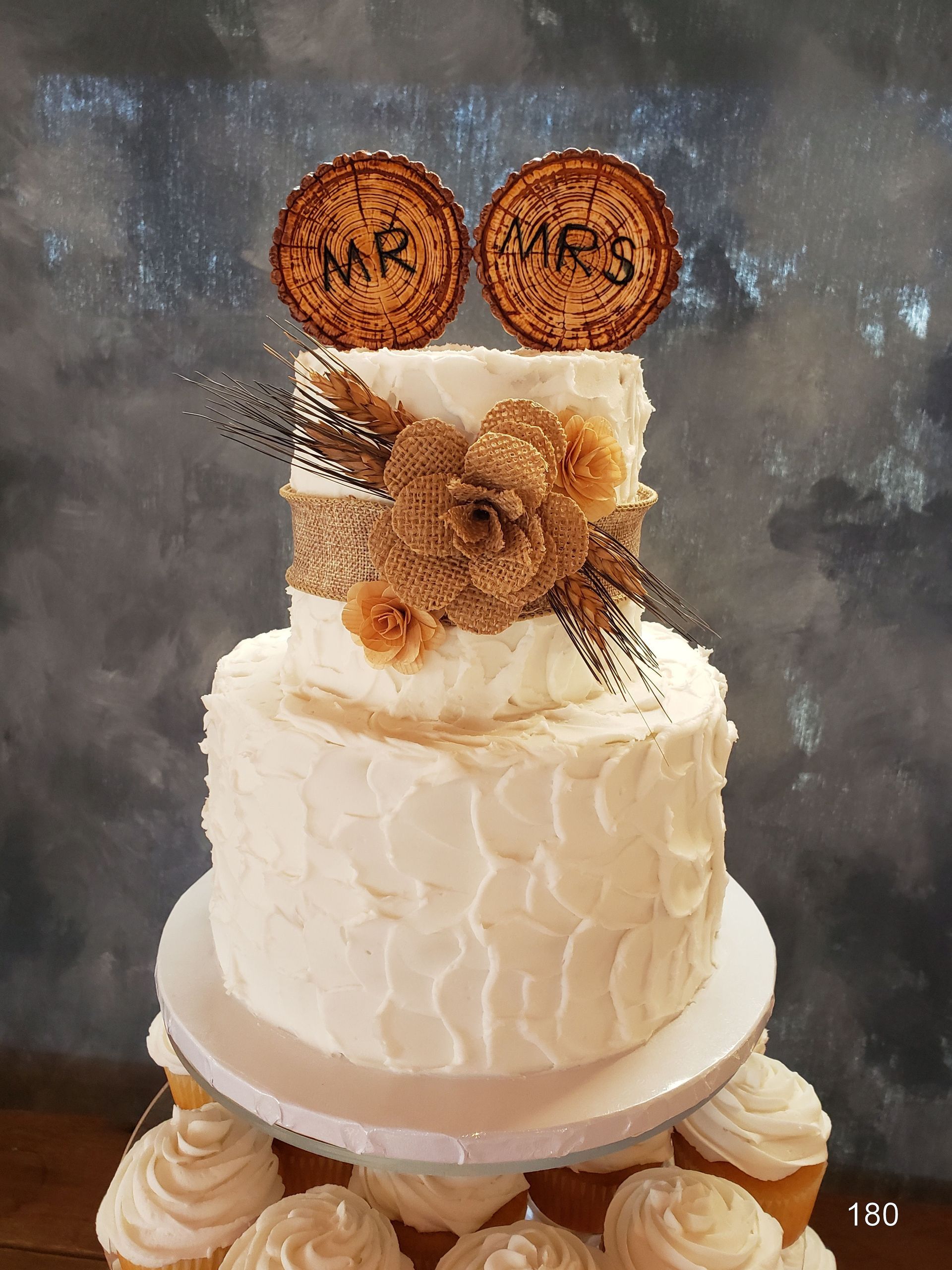 White tiered cake with floral frosting and gold “MR” and “MRS” cookies on top
