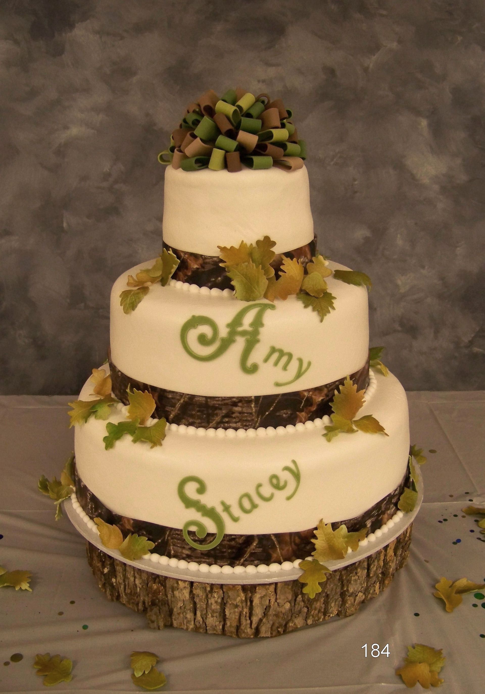 Three-tier white cake with green “Amy” and “Stacy” icing, decorated with autumn leaves and colorful cubes