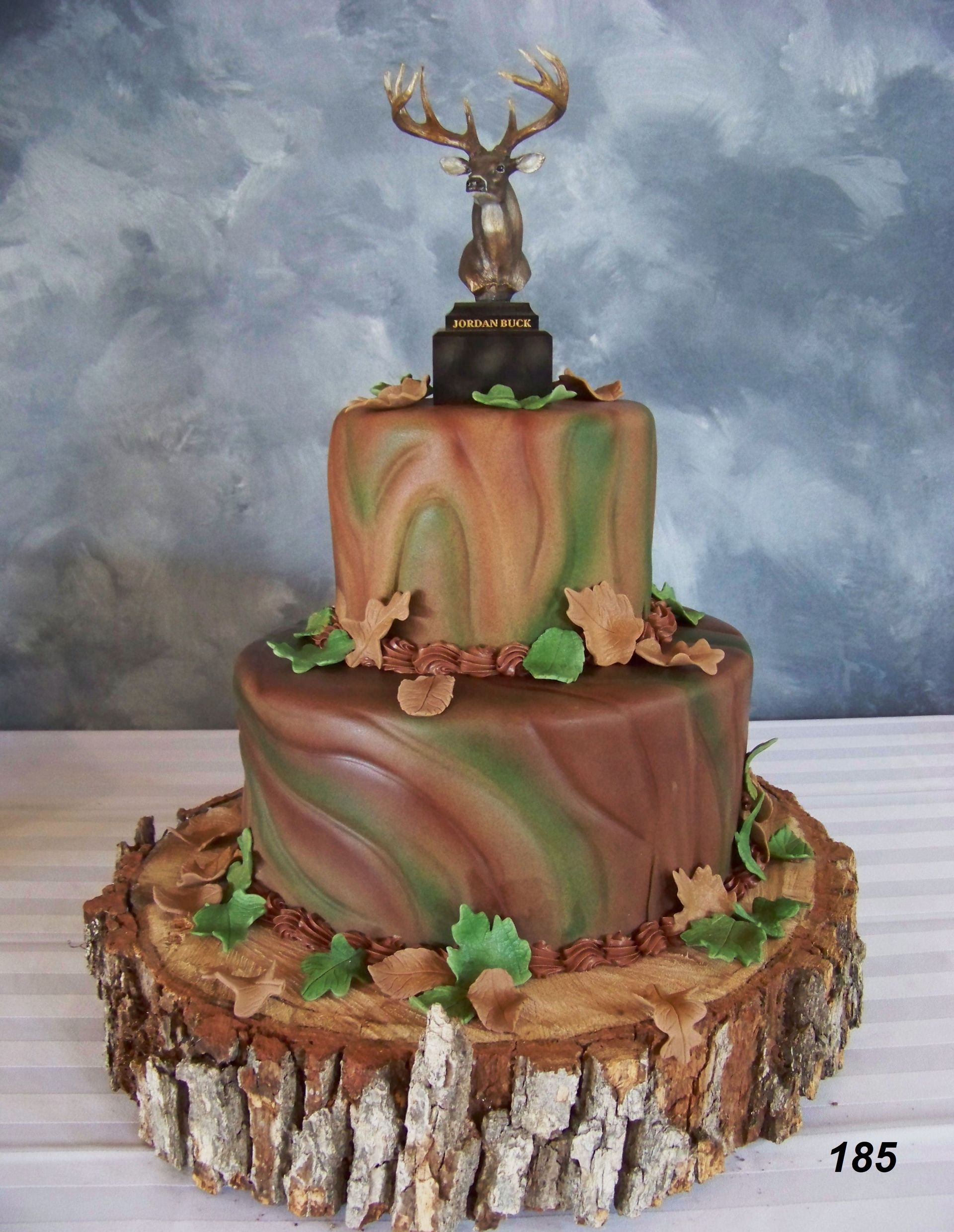 Two-tier deer-themed cake with marbled brown-green frosting and bark-like icing base
