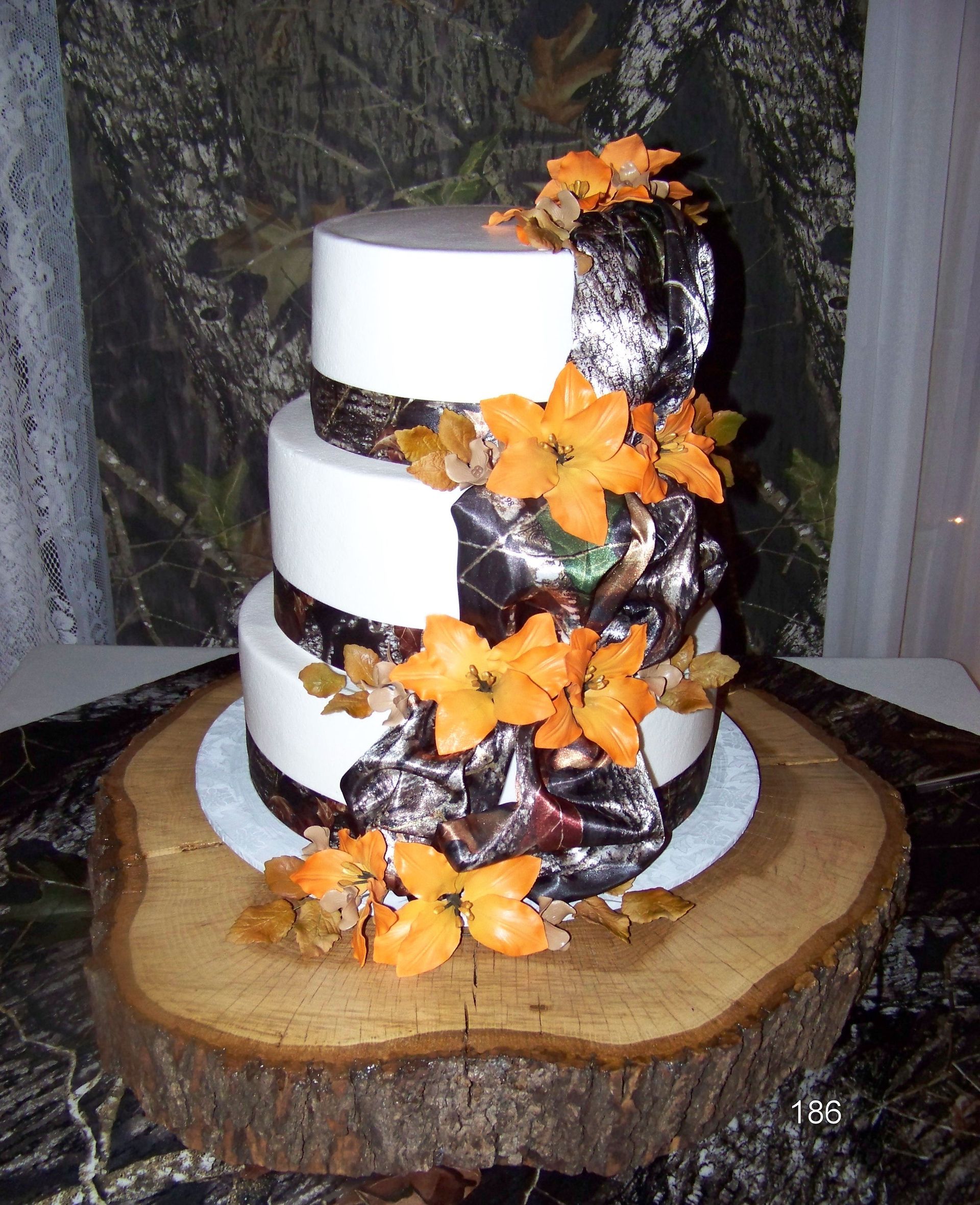 Three-tier white cake with dark chocolate drips and orange flowers on a wooden slab centerpiece