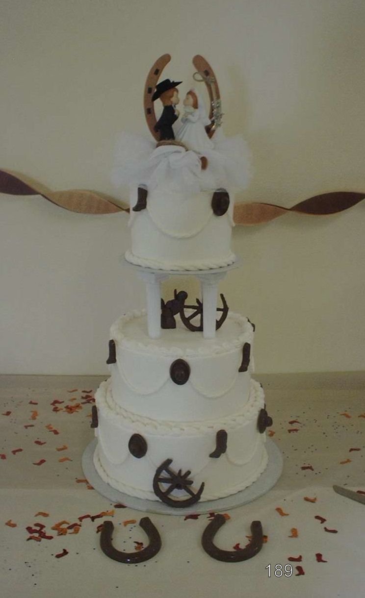 White tiered cake with black nautical decorations and a bride-and-groom topper on a table