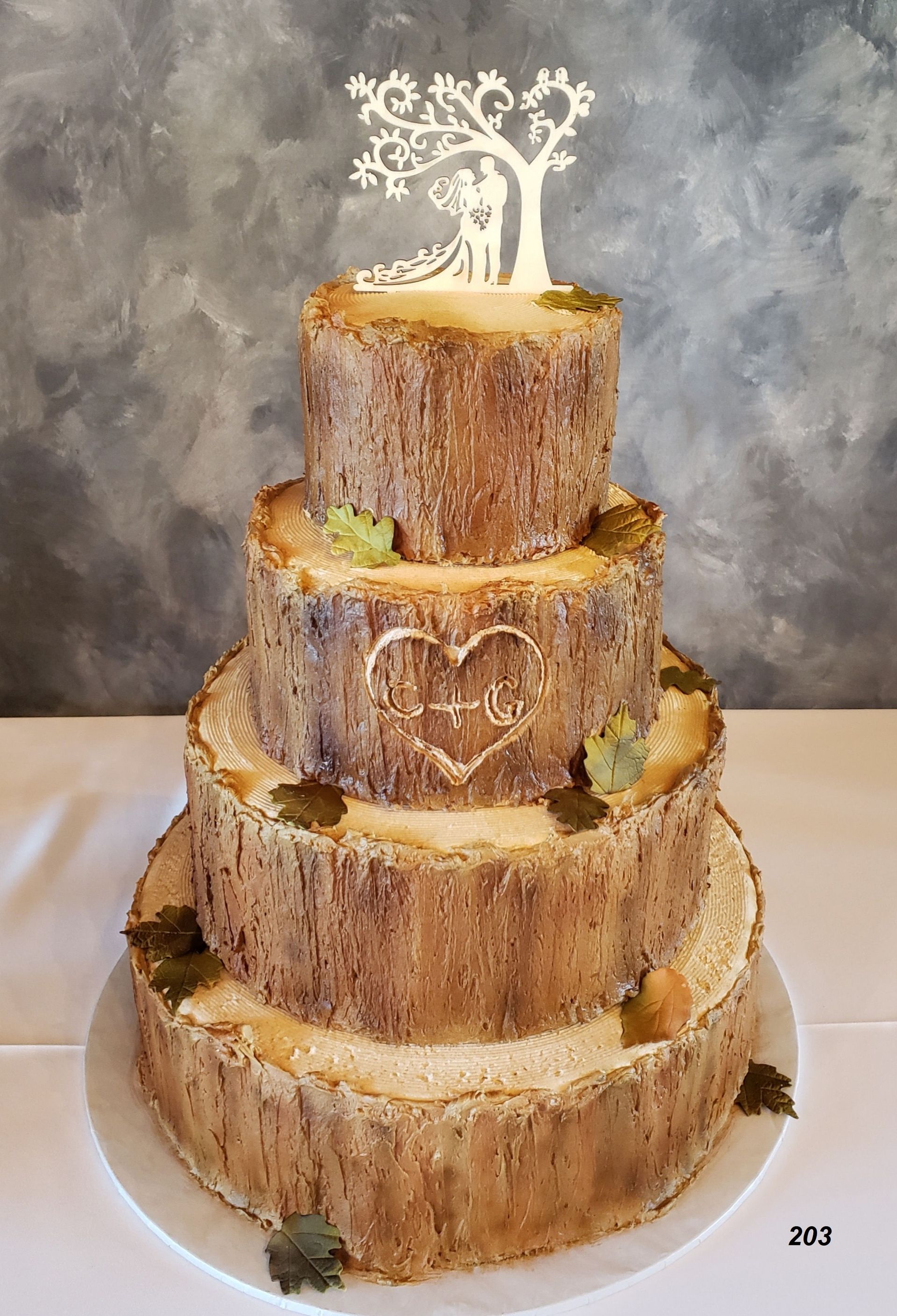 Five-tier rustic tree stump wedding cake with white topper on a gray backdrop