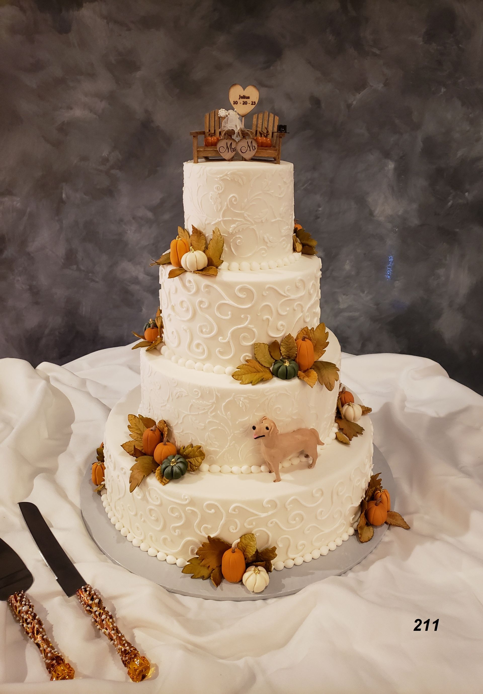 Three-tier white wedding cake with orange flowers and autumn leaves on a draped table