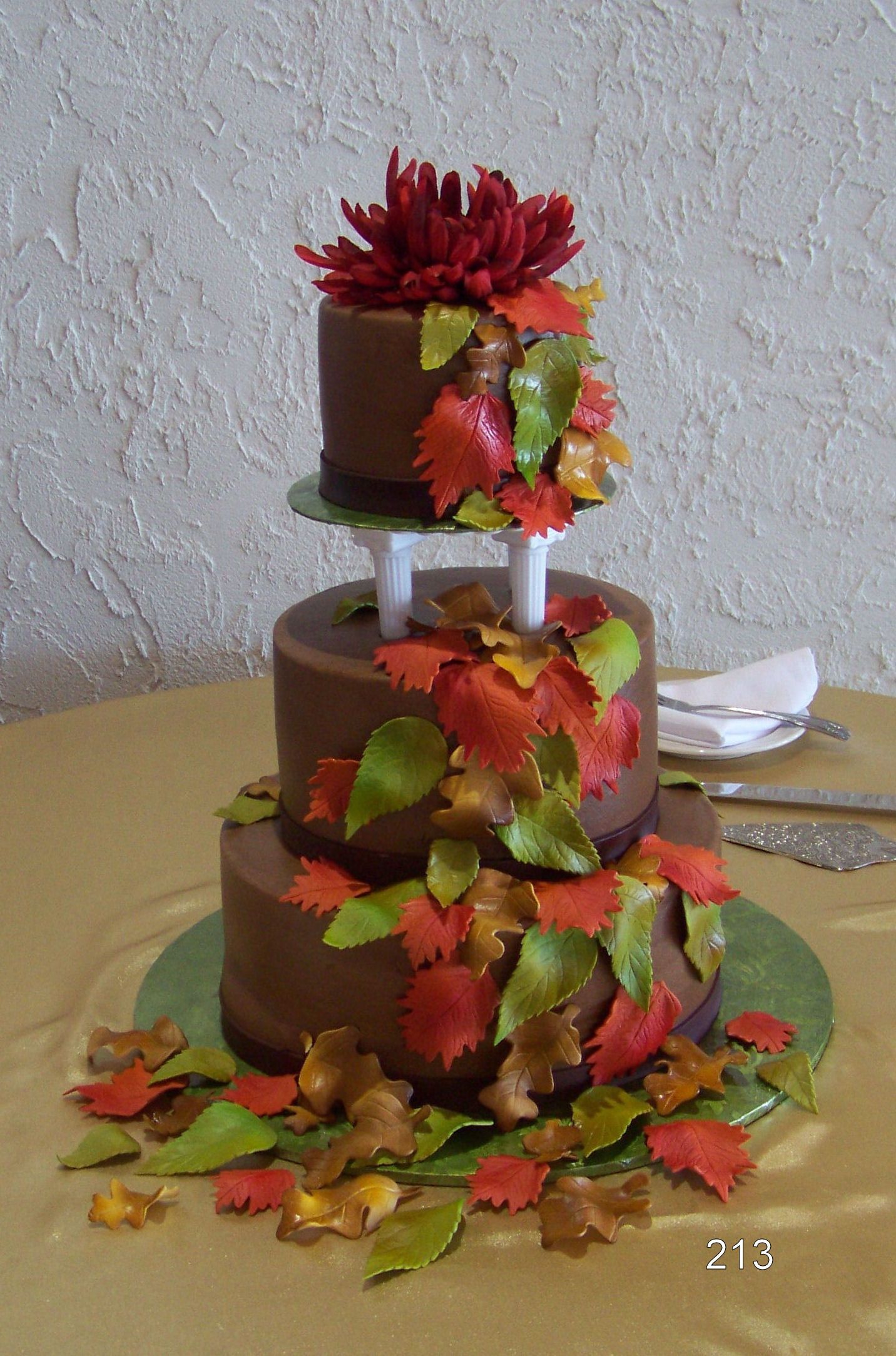 Three-tier decorated cake with red and orange leaves on a table