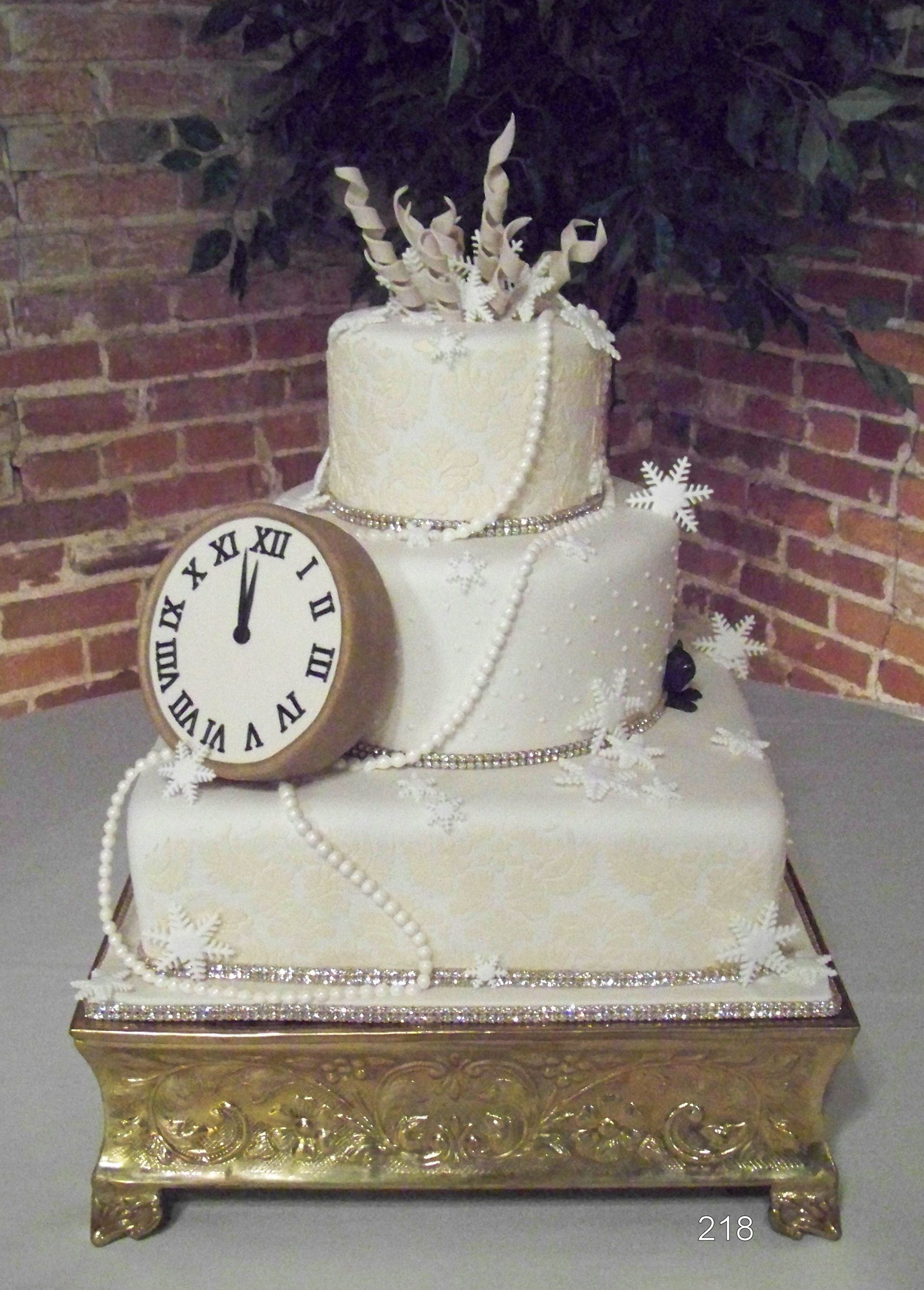 Three-tier white cake with pearl trim and a clock decoration on an ornate gold stand