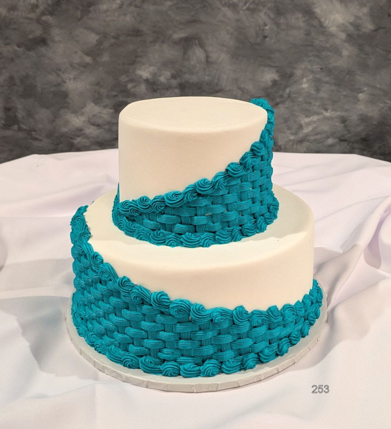 Two-tier white cake with bright teal textured frosting wrapped around the sides