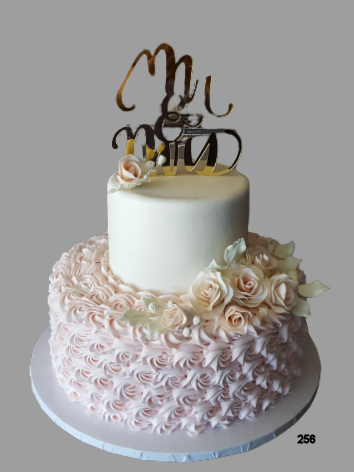 Two-tier white and pink rosette cake with gold topper on a white stand