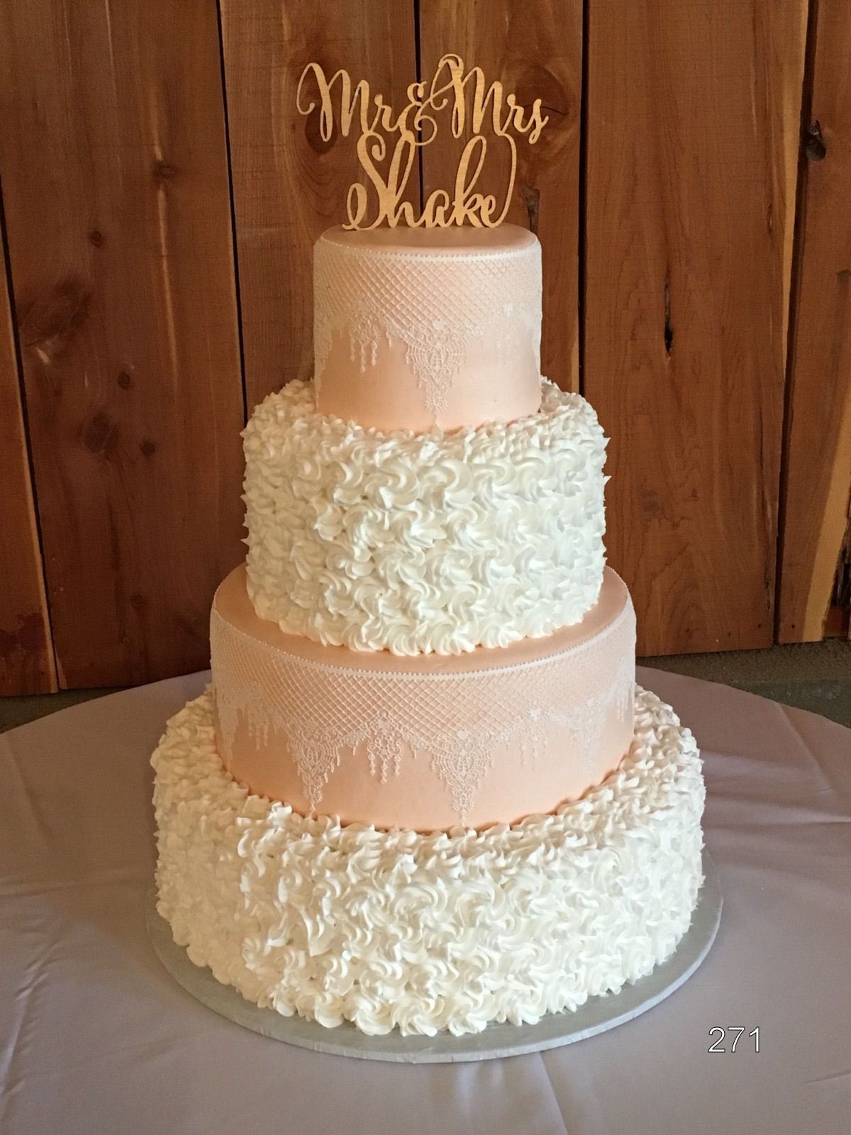 Three-tier ivory wedding cake with white floral frosting and gold topper on a table