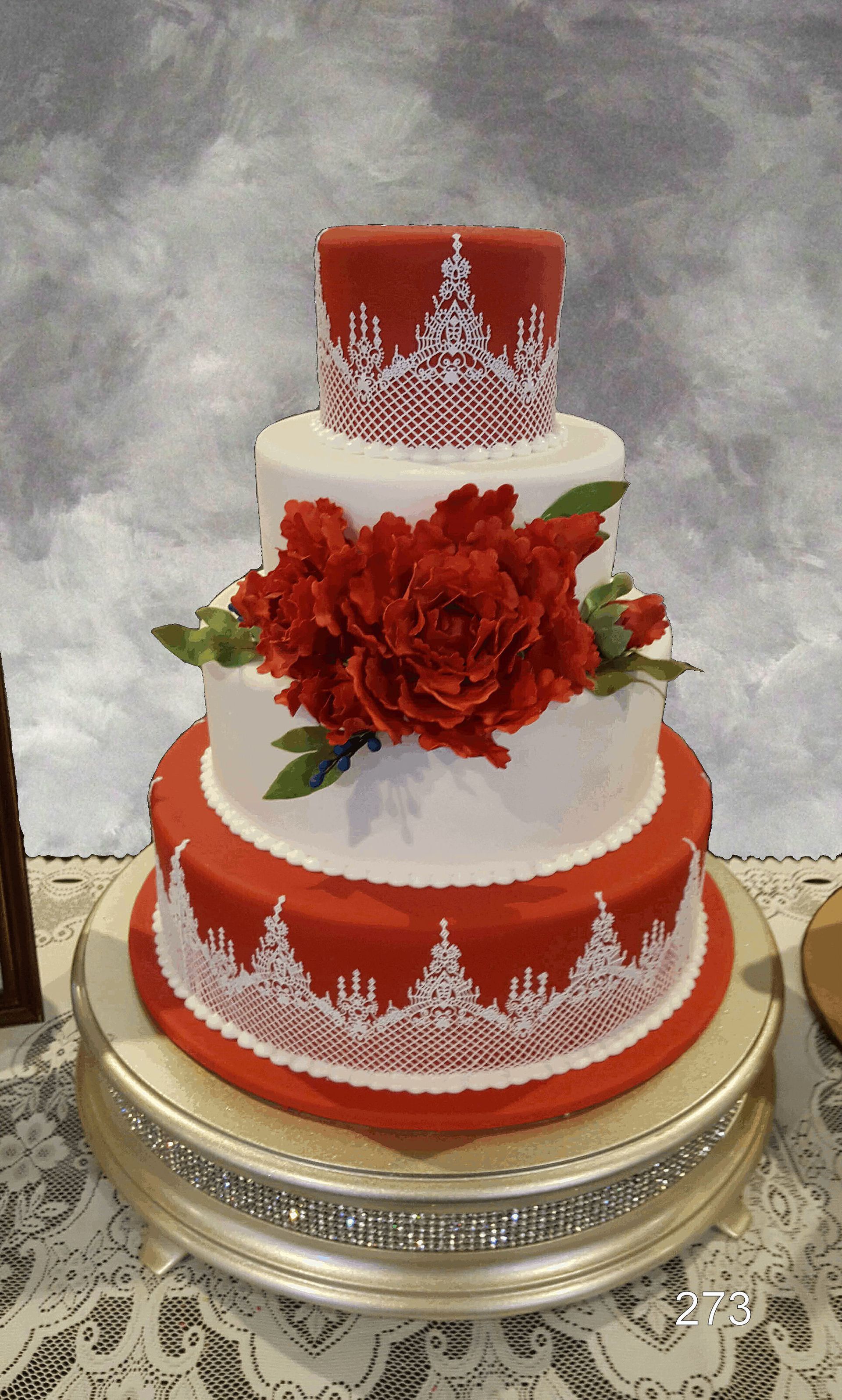 Three-tier red and white decorated cake with red flowers on a silver stand