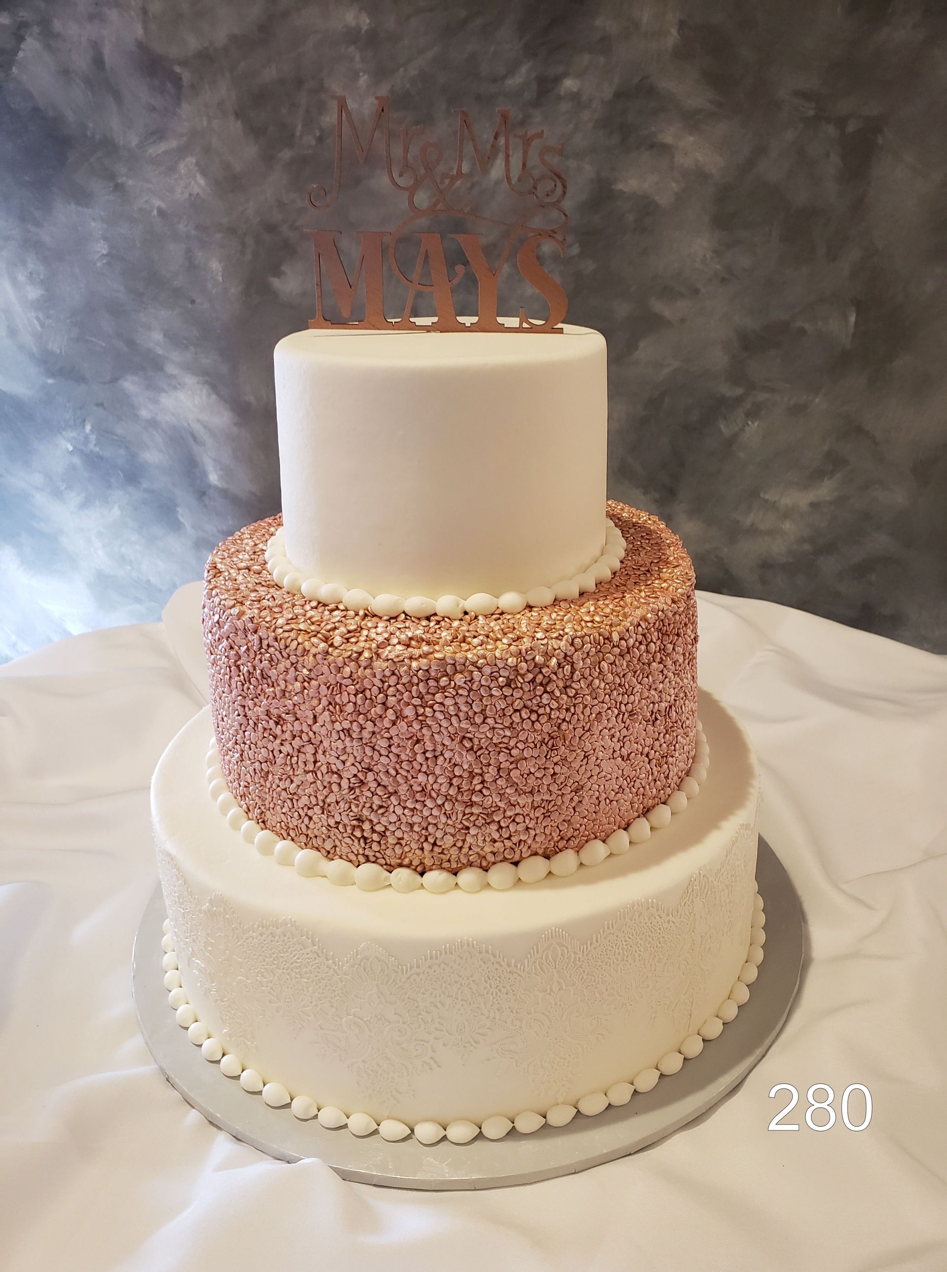 Three-tier white and pink cake with a “25” topper on a silver stand.