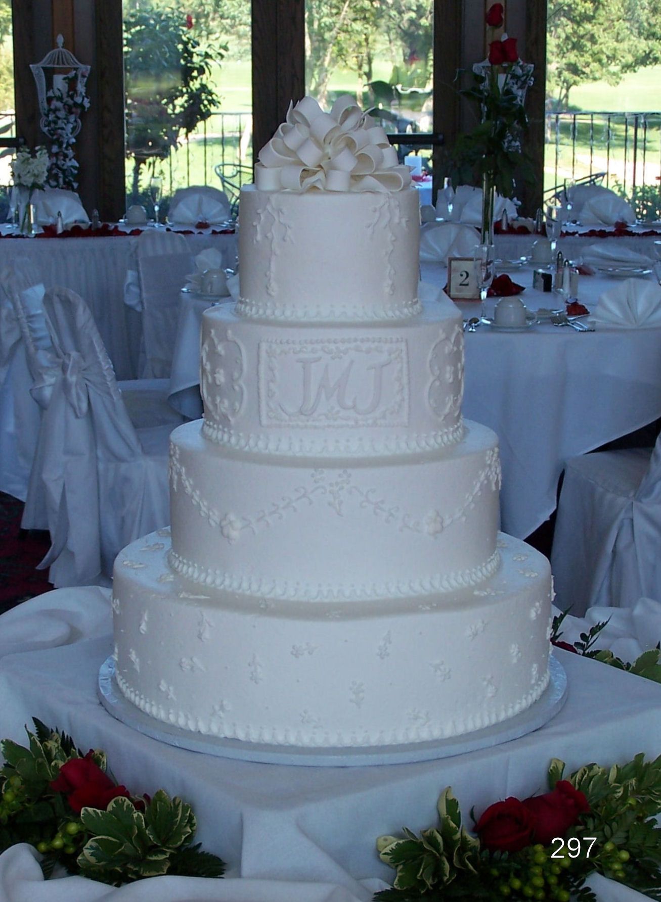 Four-tier white wedding cake with floral decorations on a reception table