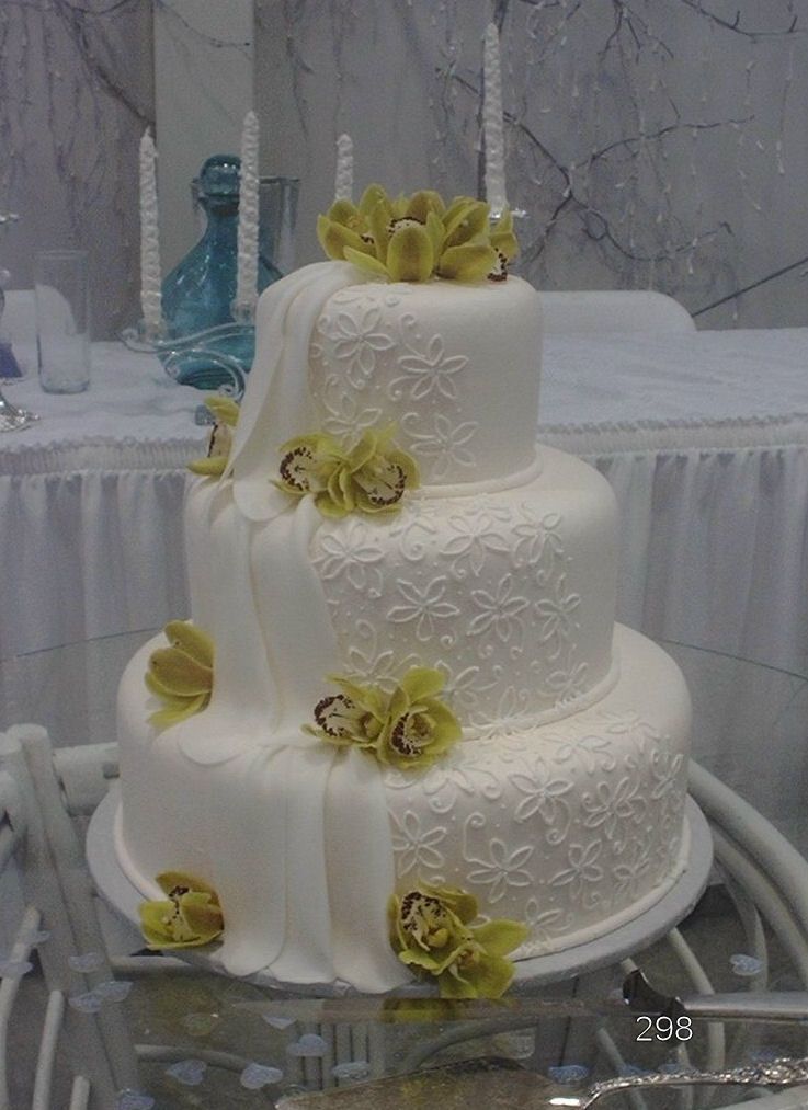 Three-tier white wedding cake with yellow flower decorations on a table