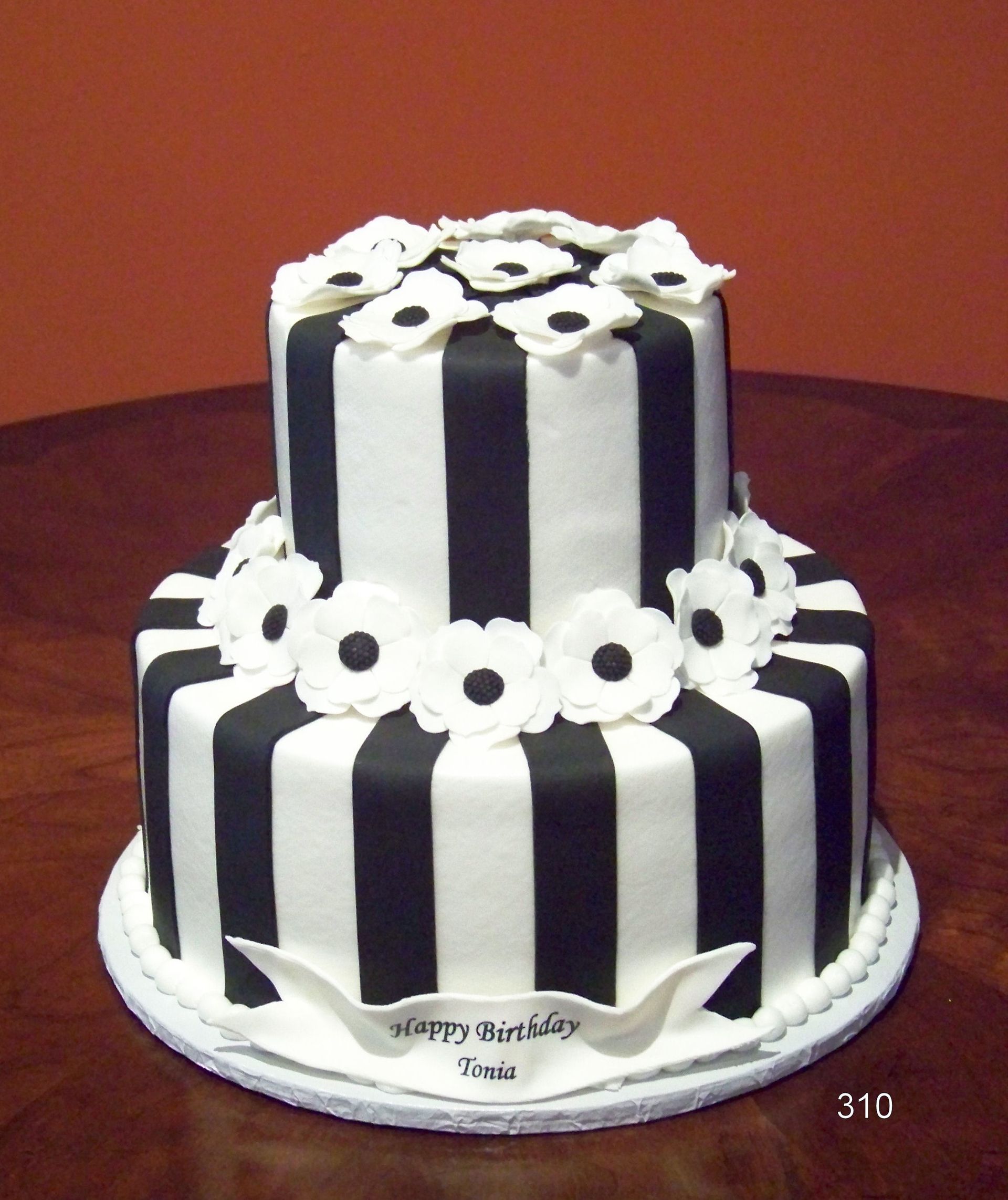 Two-tier black-and-white striped cake with white flower decorations on a white base