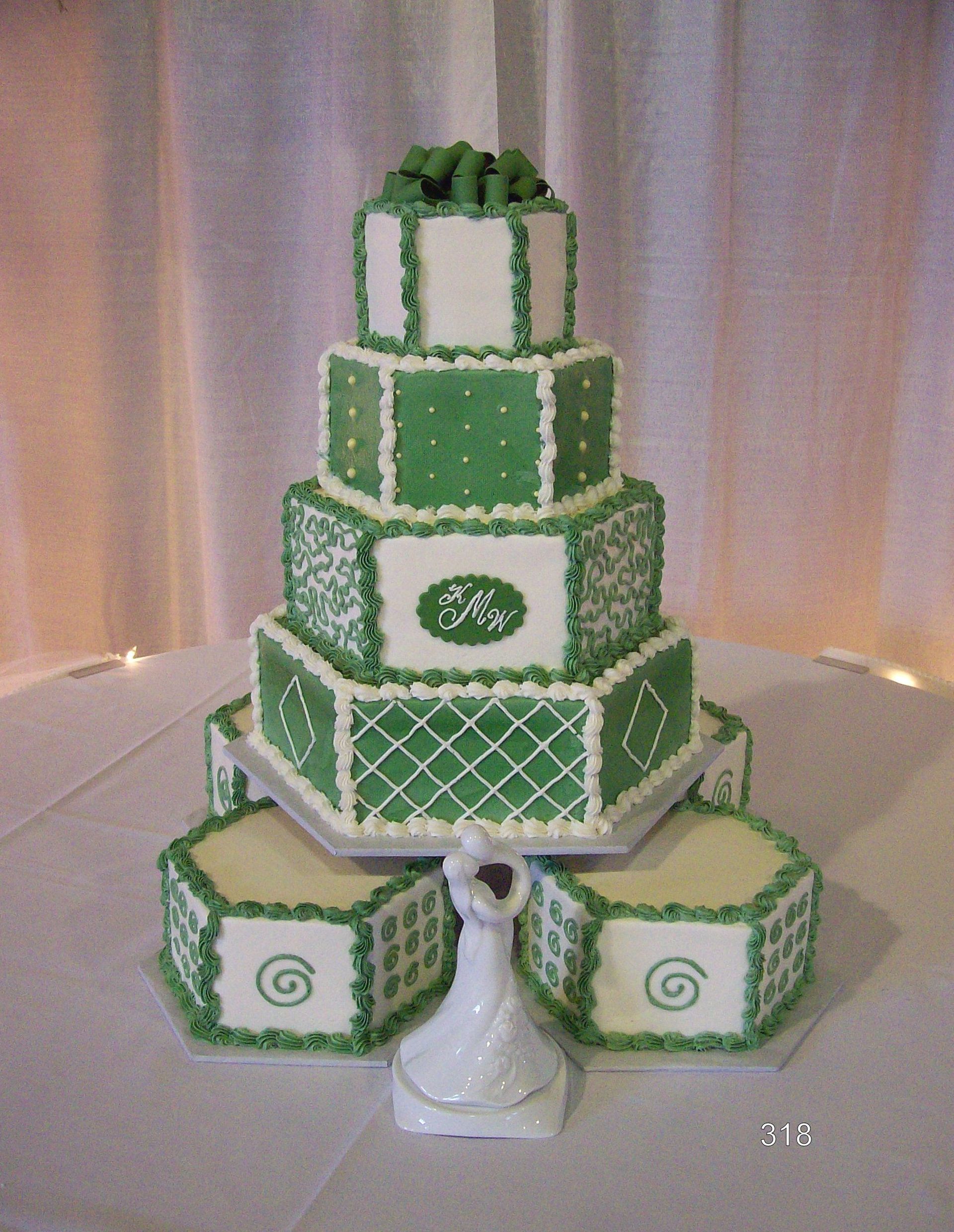 Green-and-white tiered cake on a table, decorated with spiral and lattice patterns, with two matching side cakes