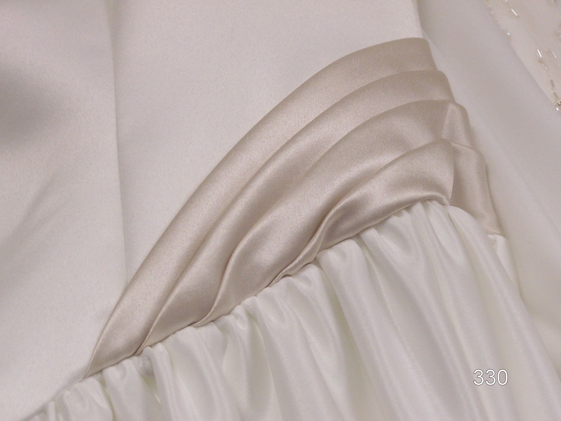 Close-up of a white pleated fabric detail with layered folds and gathered stitching