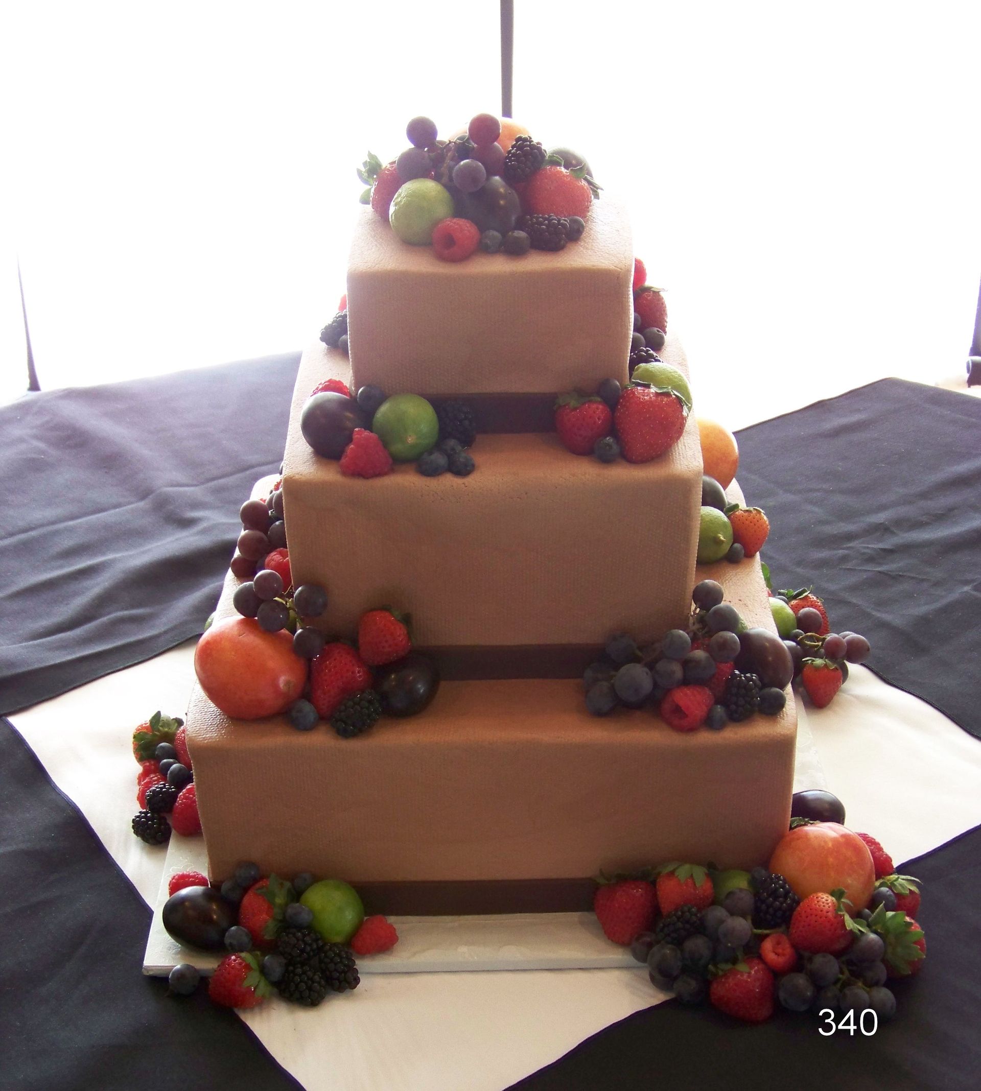 Tiered wedding cake decorated with berries and fruit on a table