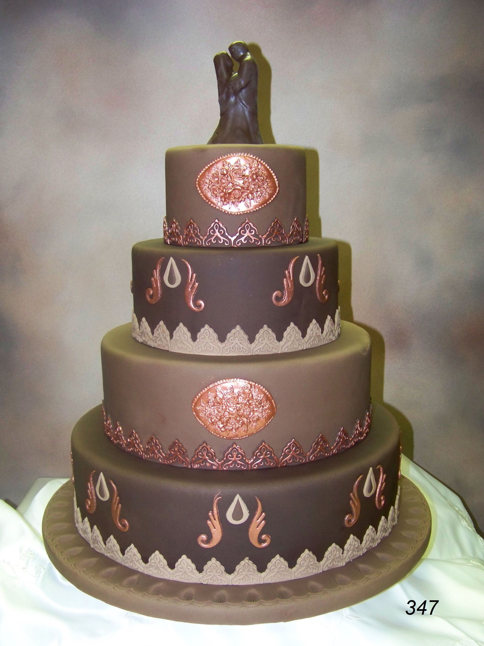 Four-tiered decorated chocolate and gold wedding cake on a stand
