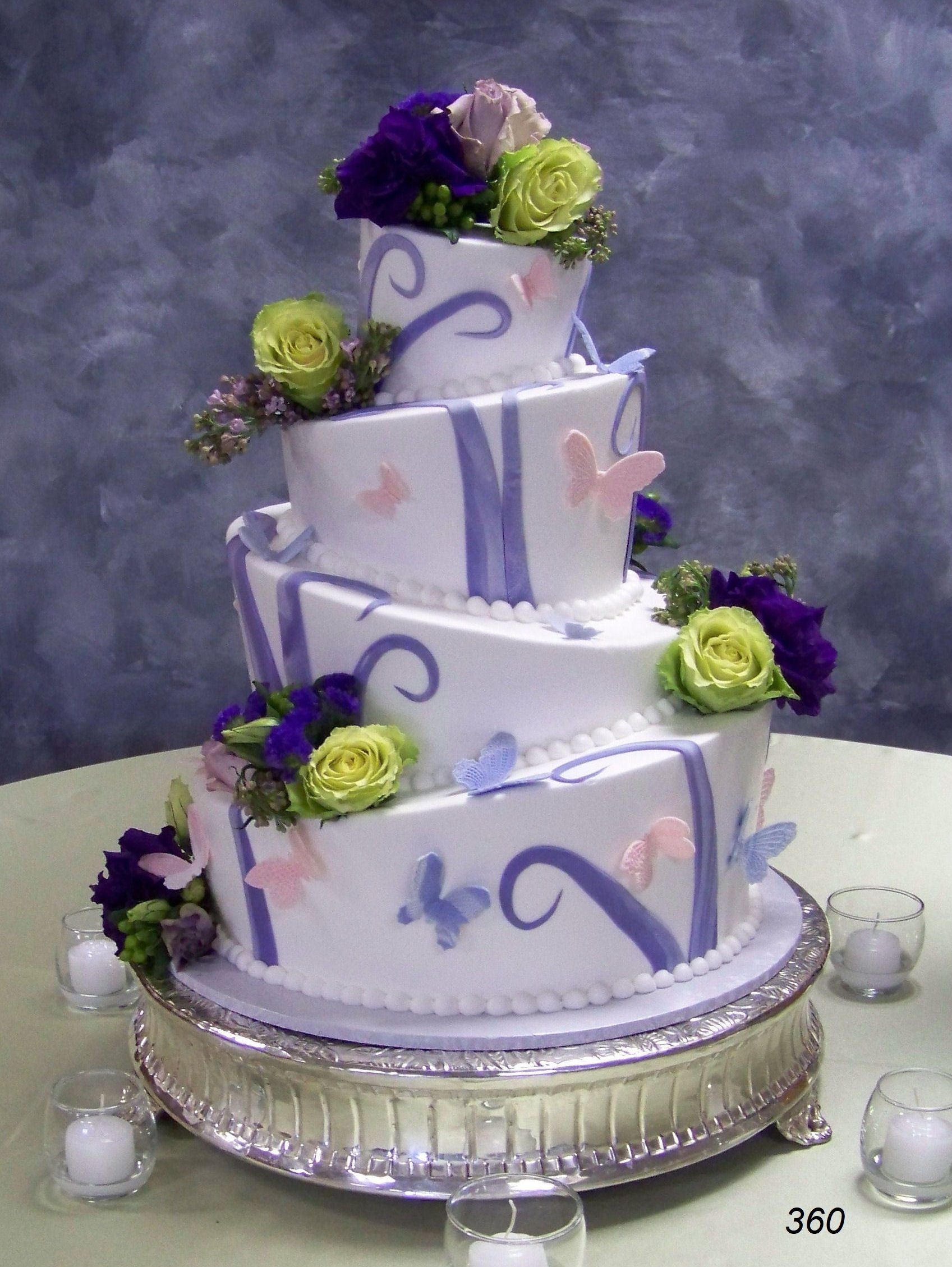 Three-tier white cake with purple swirls and green flowers on a silver stand