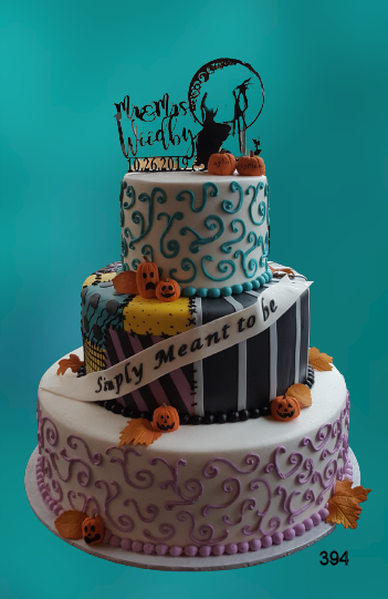 Three-tiered decorated cake with teal, purple, and black icing and a “Happy Mother’s Day” banner.