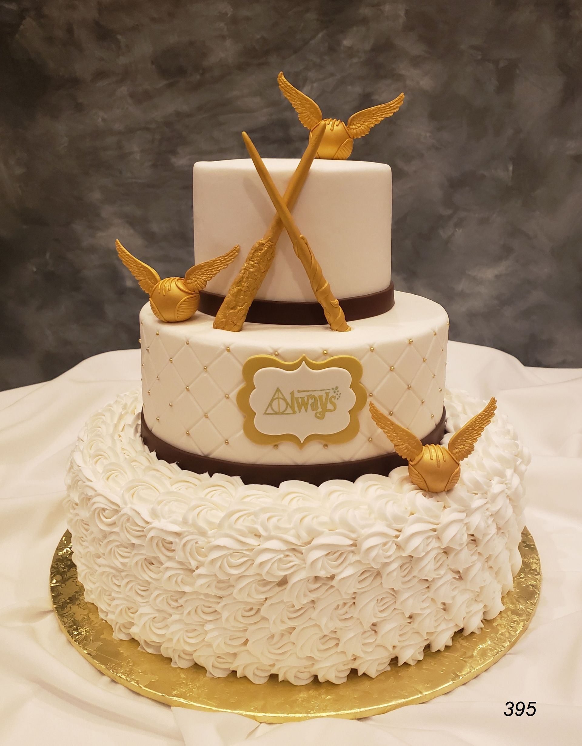 Three-tier white and gold cake with gold butterfly decorations on a table