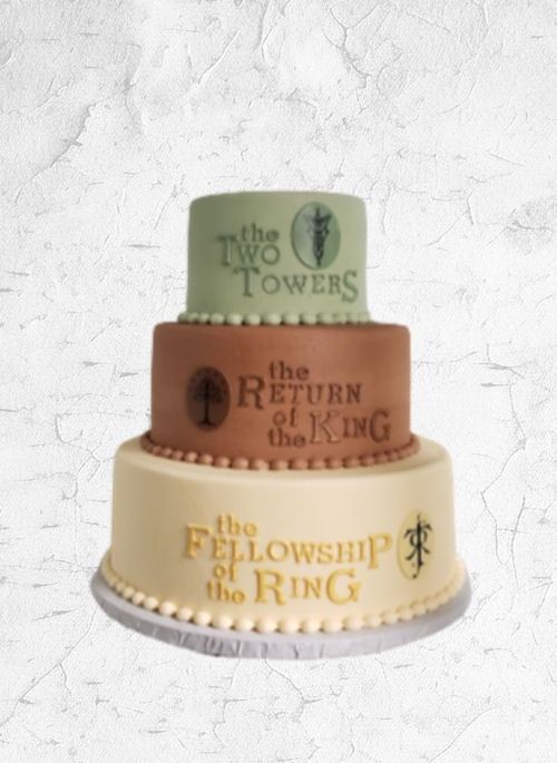 Three-tiered cake with Lord of the Rings titles: The Fellowship of the Ring, The Two Towers, The Return of the King