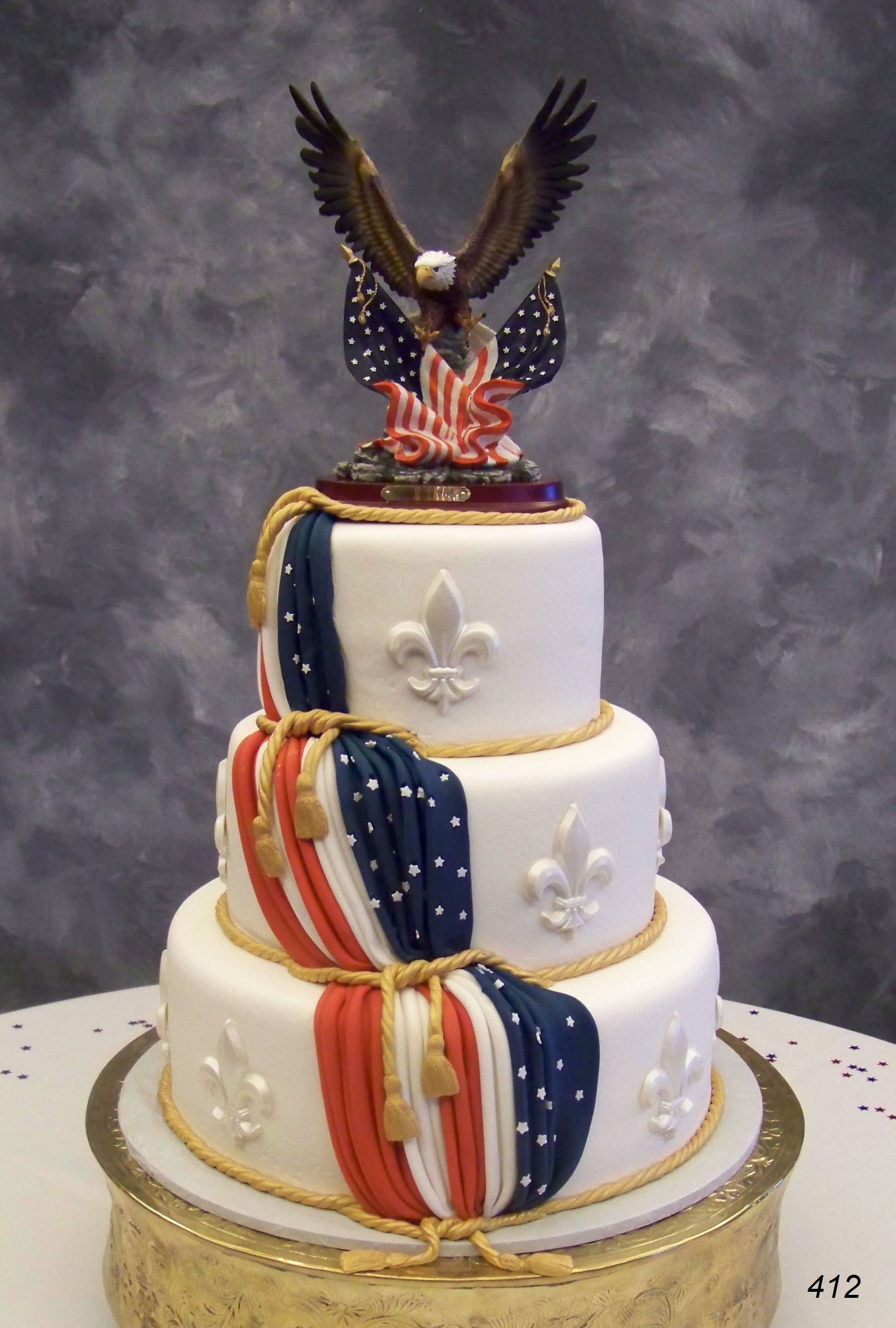Three-tier patriotic cake with red, white, and blue drapes and an eagle topper