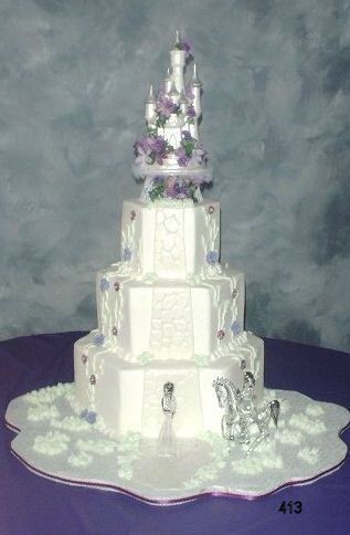 White tiered wedding cake with pastel floral decorations on a silver stand