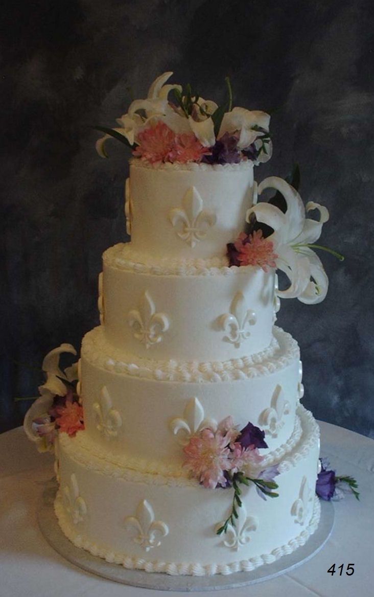Three-tier white wedding cake with floral decorations and swirled icing on a dark background