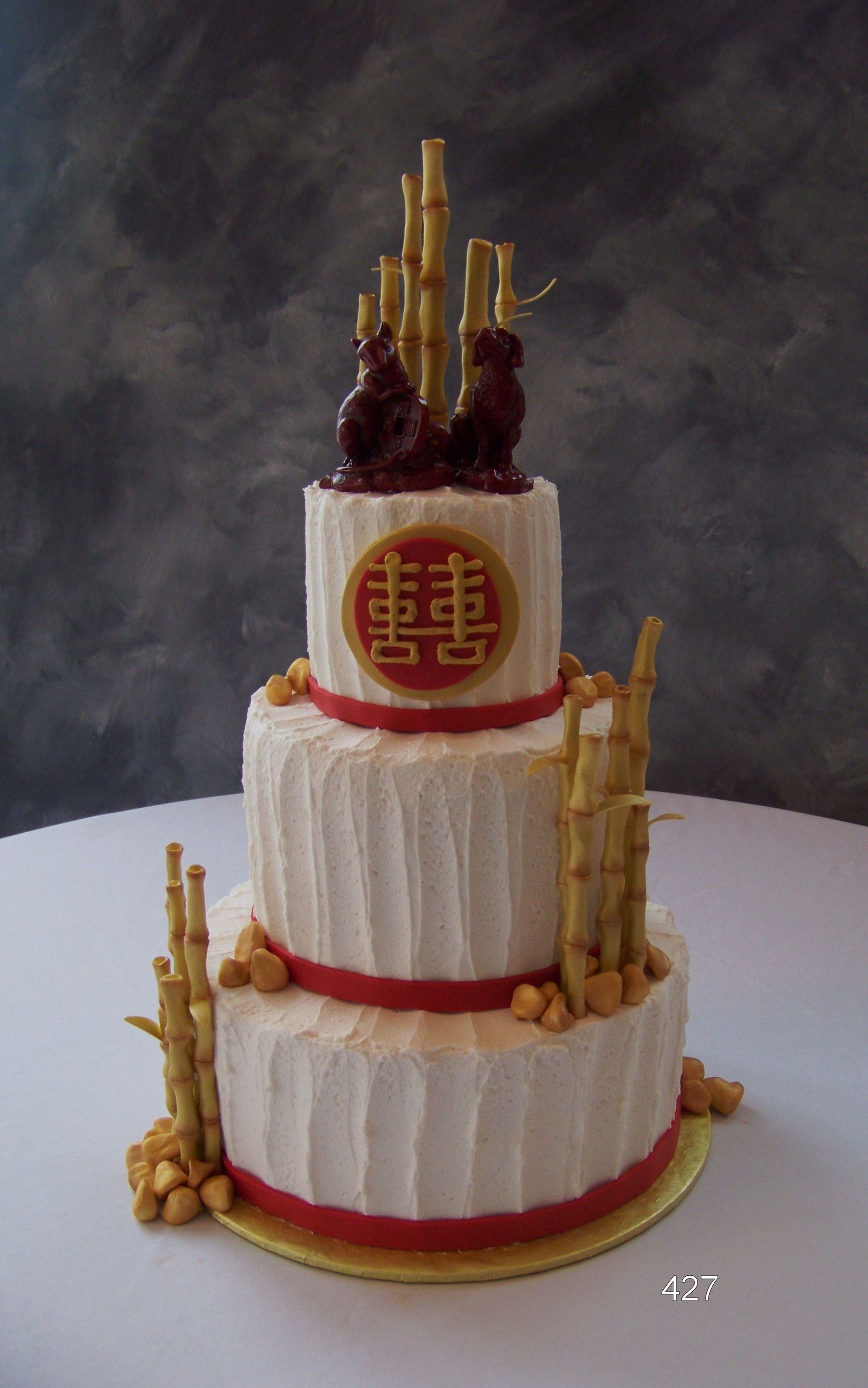 Three-tier white cake with red accents and gold Chinese-style decorations on a dark background