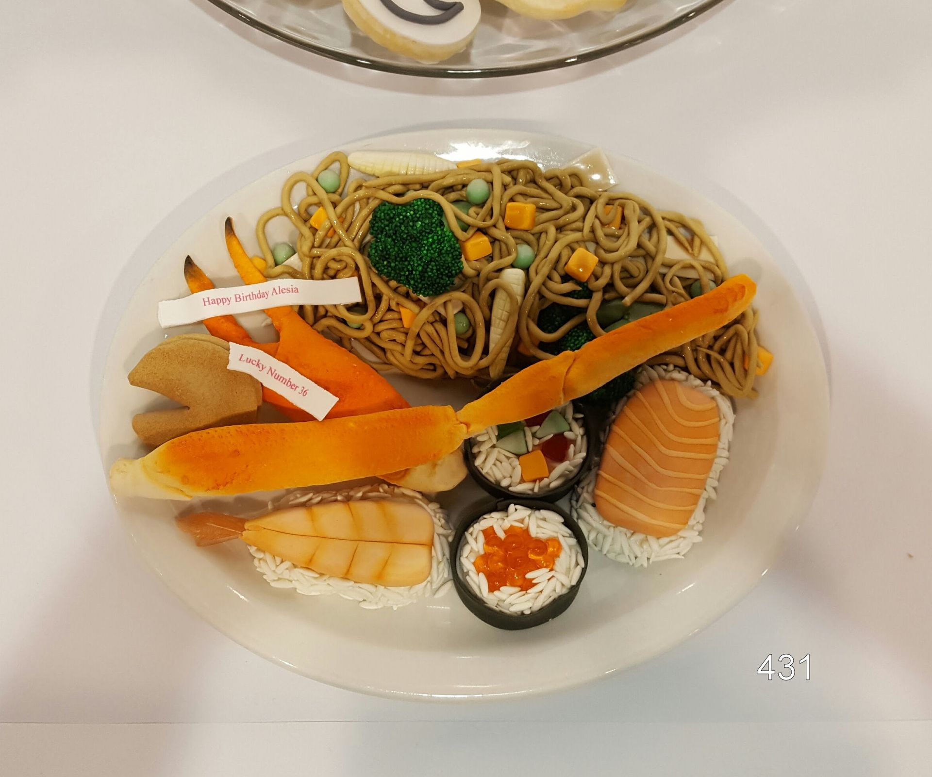 Sushi platter with assorted rolls, sashimi, and garnishes on a clear plate