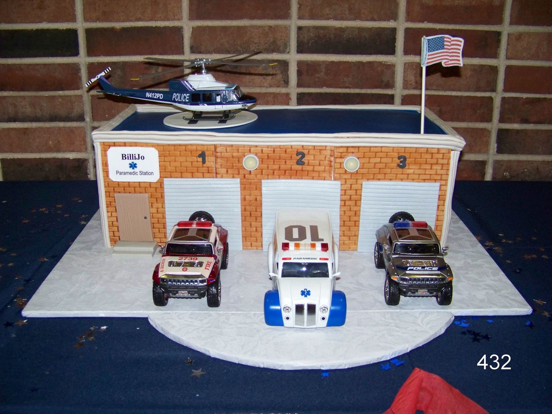Toy fire station display with three vehicles, a helicopter on the roof, and a small American flag